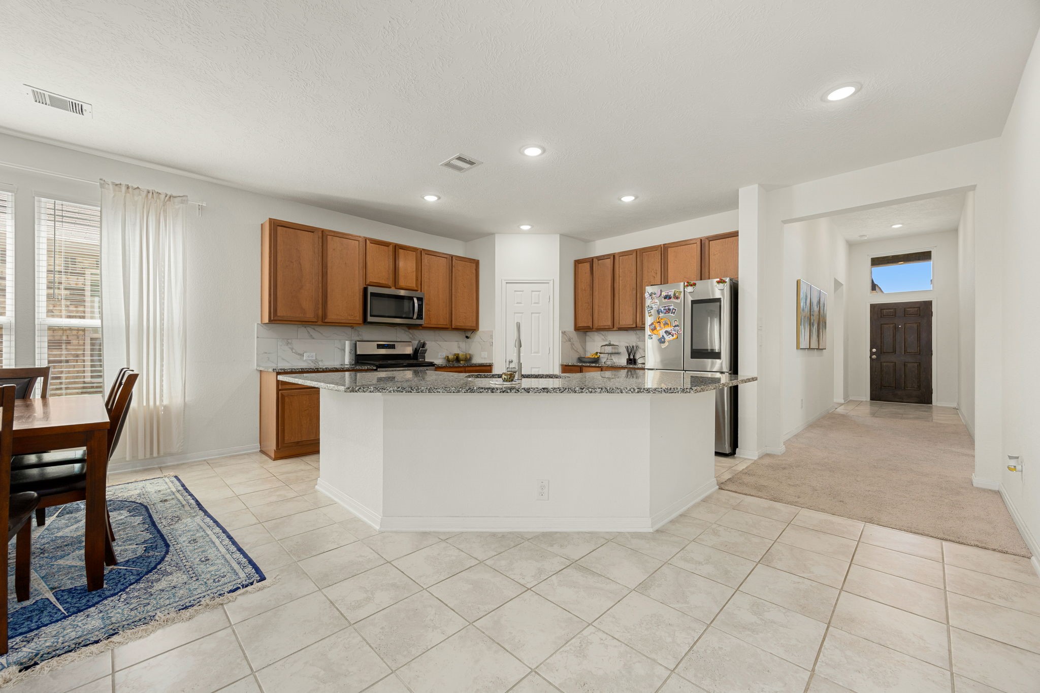 This perspective highlights the exceptional flow from the front doorway straight into the central meeting area. Greet family and guests as they arrive in the bright, open great room.