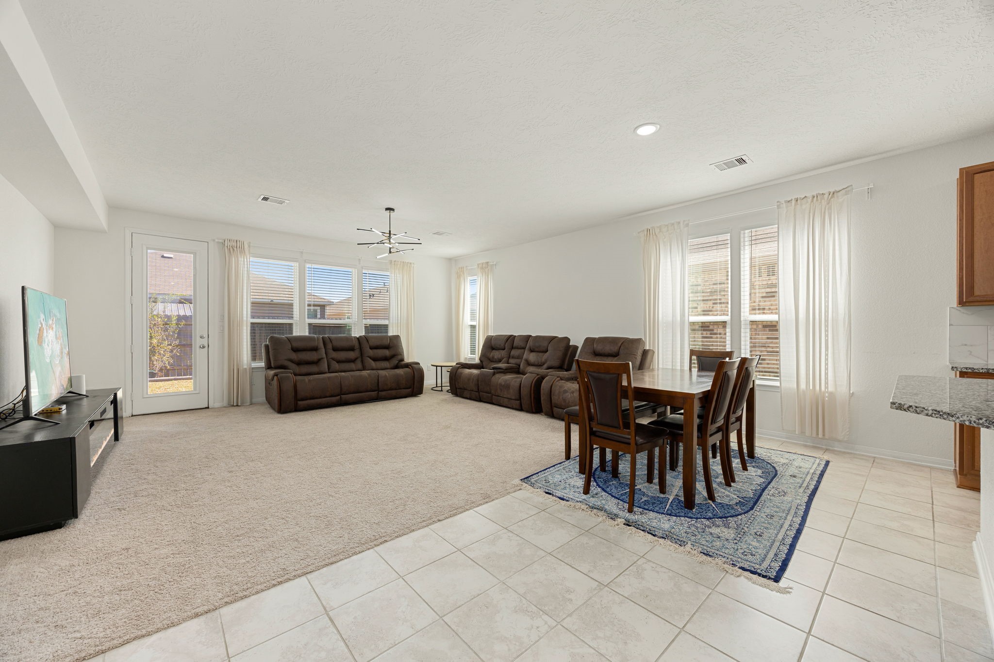 The continuous flow between the casual dining area and the spacious family room defines this exceptional open-concept floor plan. Multiple oversized windows and a glass patio door line the back wall, bathing the entire great room in soft natural light while providing lovely sightlines out to the backyard.