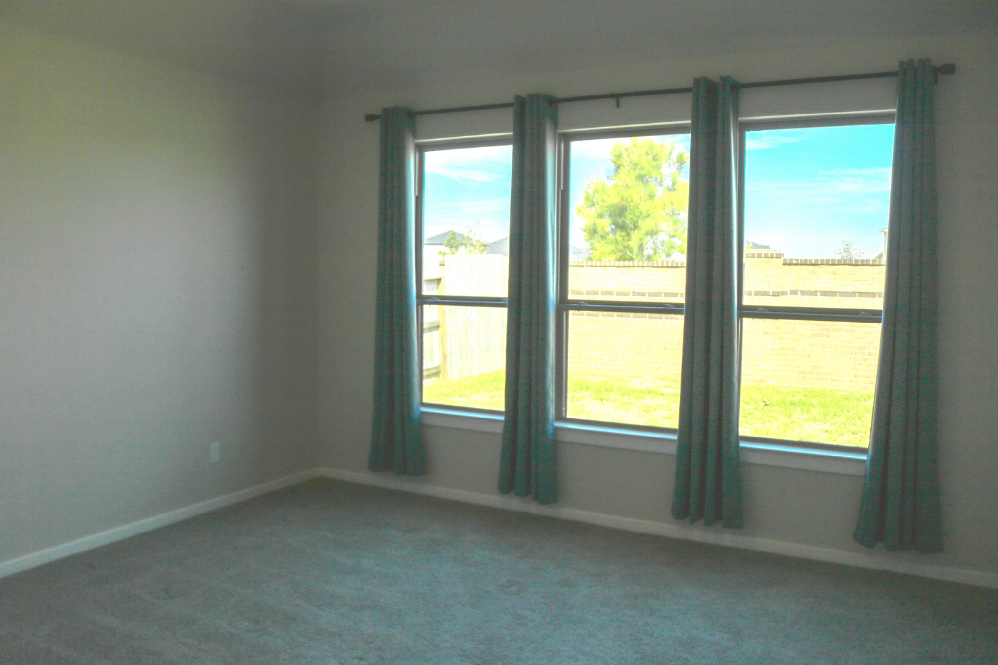 Spacious primary bedroom downstairs featuring three large windows that welcome natural light, neutral tones, and soft carpeting. A comfortable retreat with plenty of room to relax and unwind.