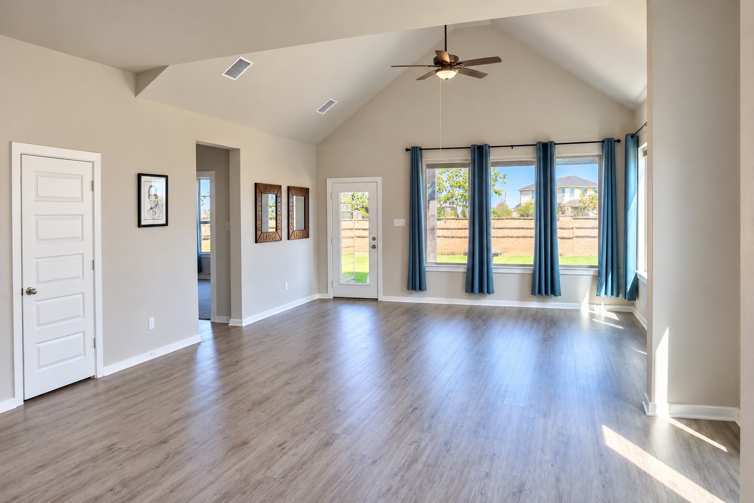 Spacious living area featuring a vaulted ceiling, abundant windows, and attractive flooring. The open layout creates an inviting space for everyday living and entertaining, with easy access to the kitchen and dining area.
