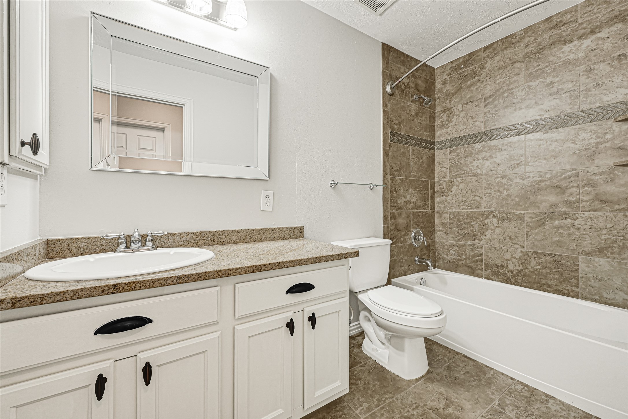 Bathroom features a shower/tub combo with tile extending to the ceiling for a custom finish.