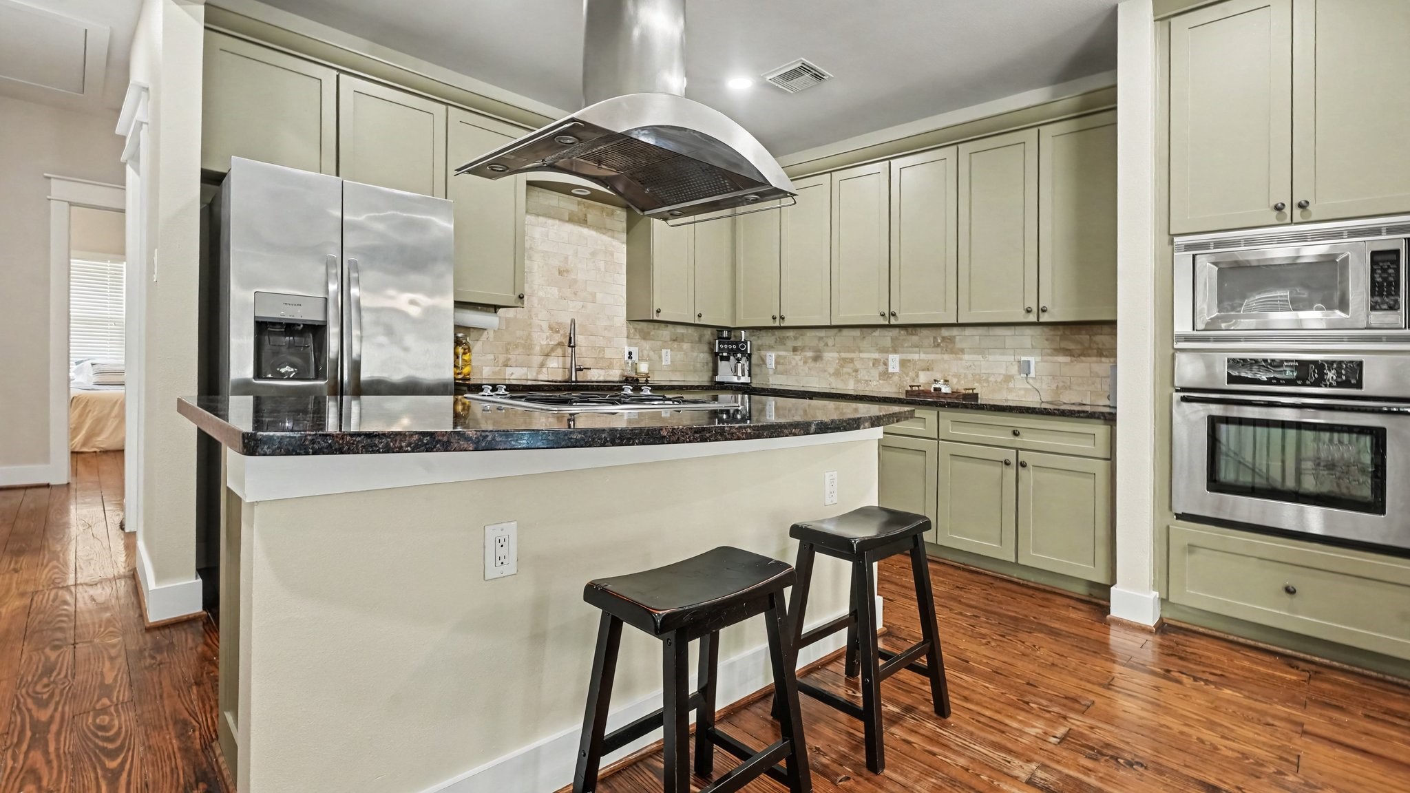 This island kitchen with gas cooktop has so much counter space and storage!  Stainless steel appliances, and tile backsplash.