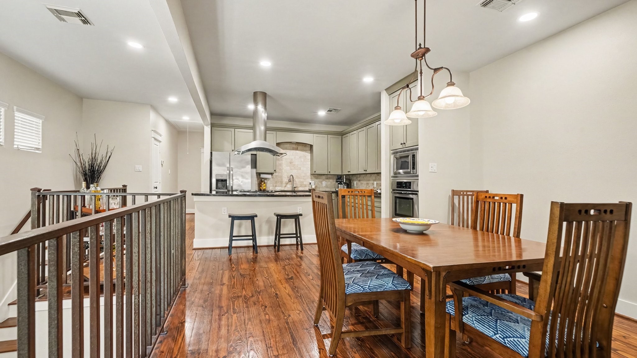 The dining room is perfectly situated between the kitchen and living room, literally an entertainer's dream layout. Iron railings run along the length of the dining room and overlook the stairwell.