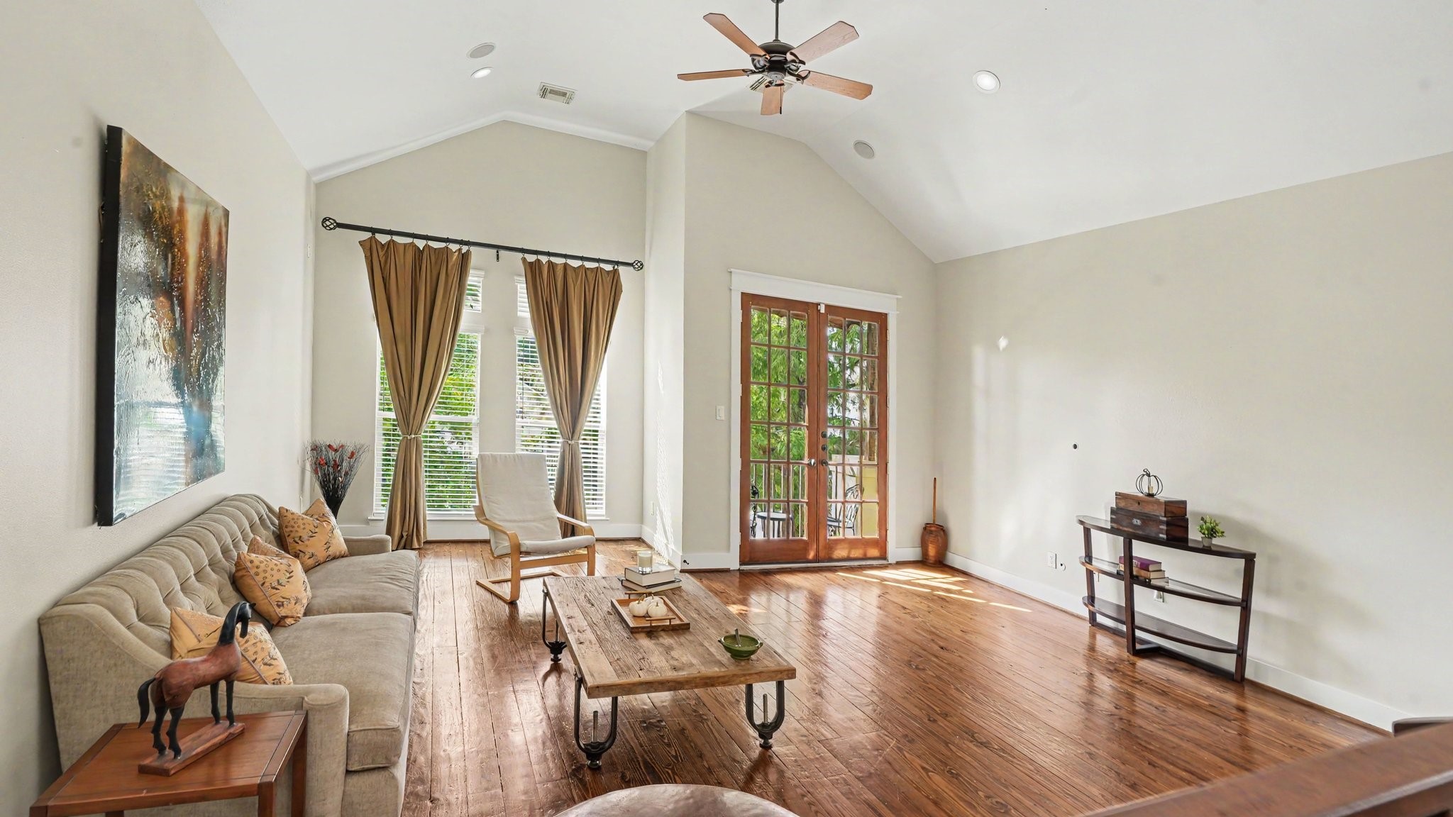 Beautiful and spacious living room lets in plenty of natural light, with high ceilings and real hardwood floors. French doors lead out to a private balcony overlooking the greenery of 2 mature trees.