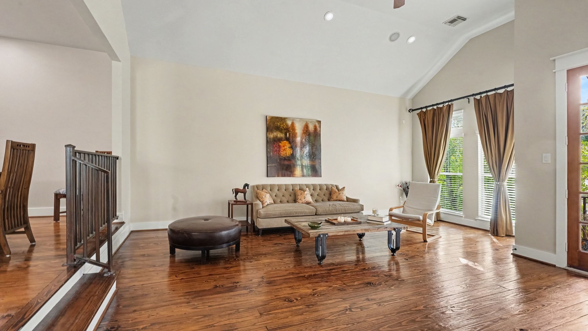 Another view of the living room shows 2 steps with cool iron railing leading up to the dining room
