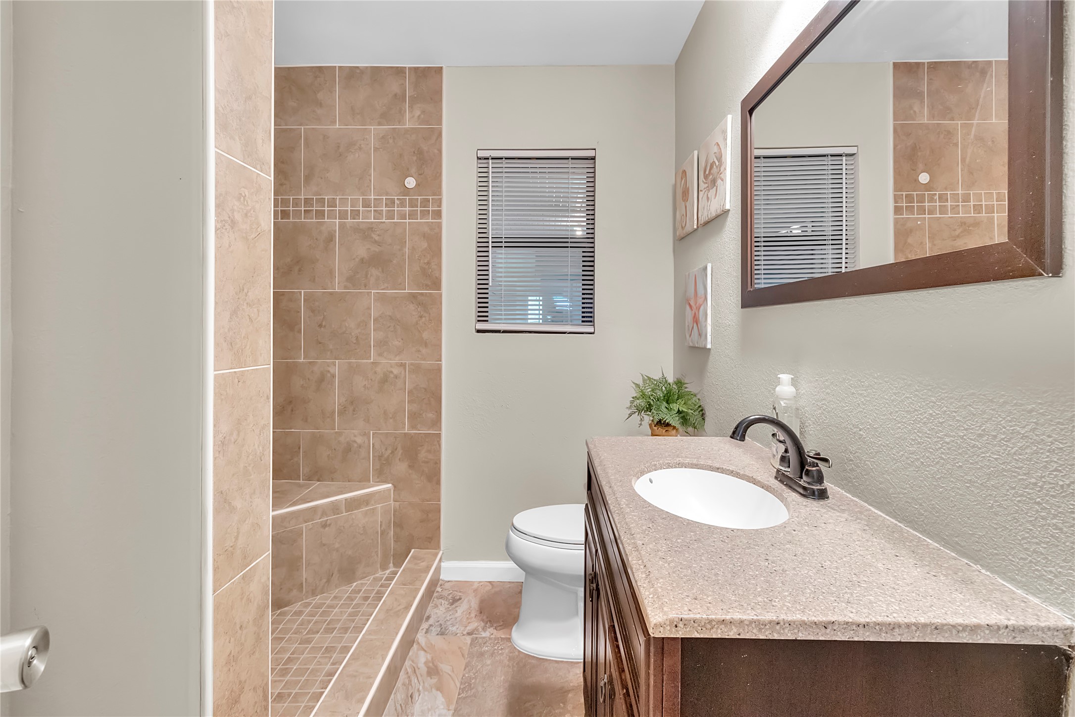 Updated full bathroom with tiled shower surround, bright vanity area, and neutral finishes.