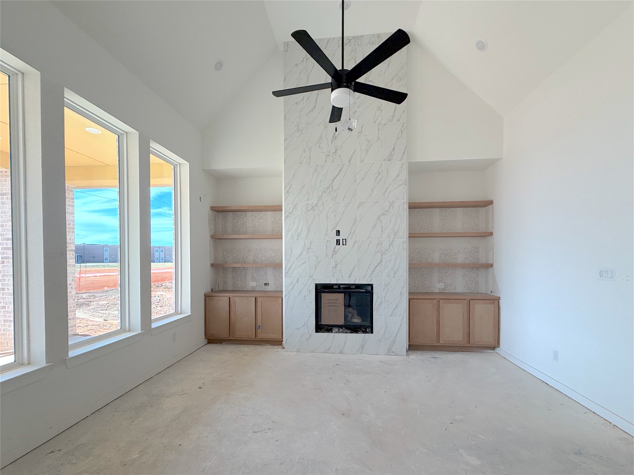 Bright family room featuring vaulted ceilings, a fireplace, and custom built-in shelving. Bright family room featuring vaulted ceilings, a fireplace, and custom built-in shelving.
