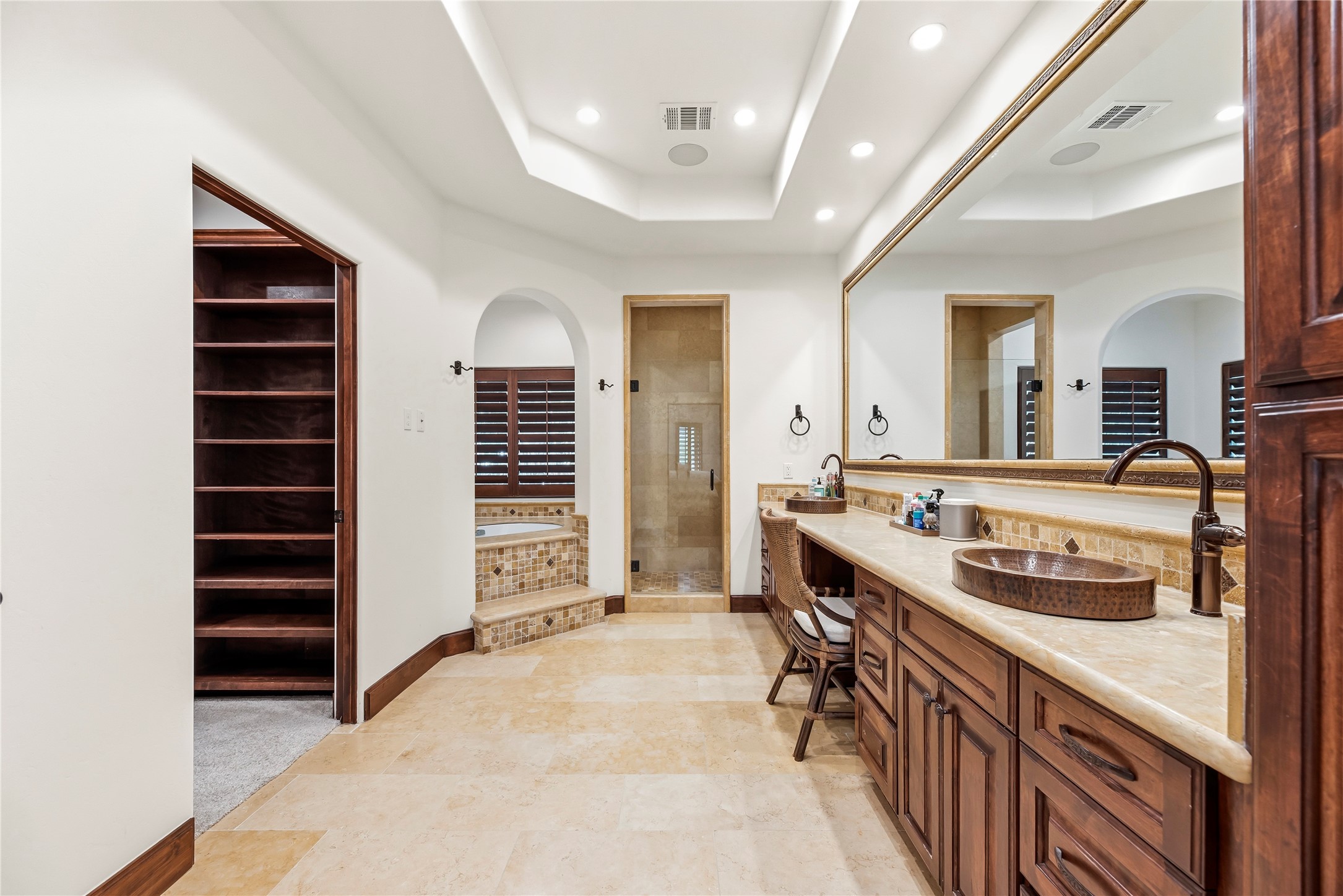 The Primary Suites en-suite bath serves as a private spa with a jetted tub, separate shower, double sinks, and a generous walk-in closet for organized luxury.