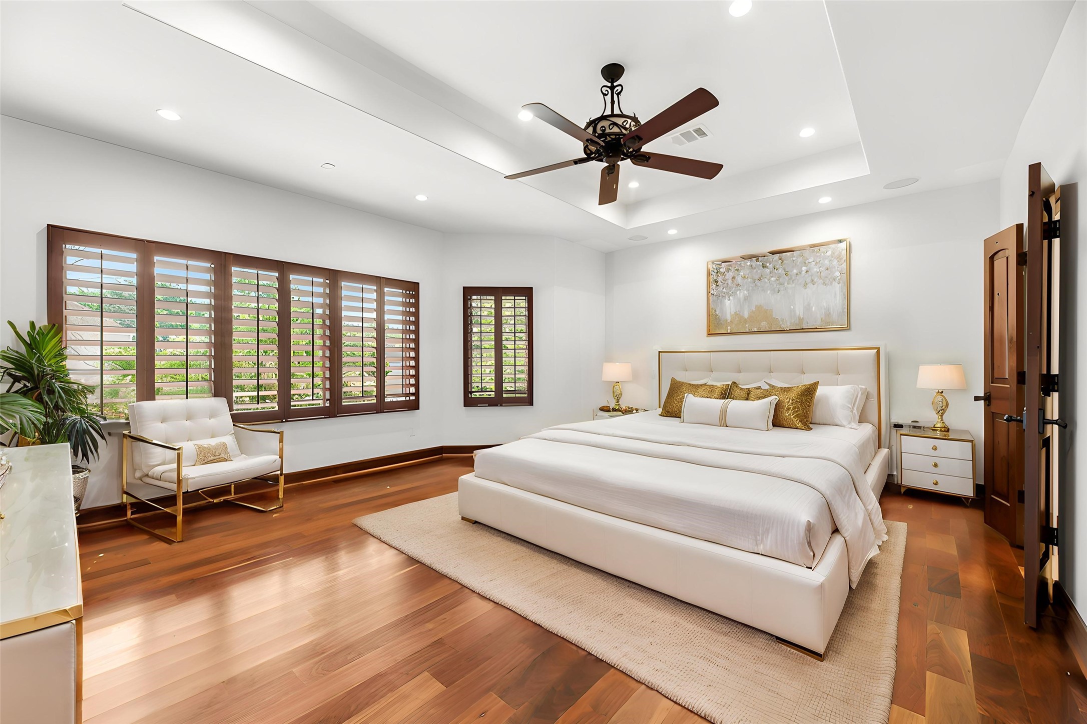 The expansive Primary Suite features tray ceilings, rich wood floors, and large windows that fill the room with a serene glow for ultimate relaxation. Virtually staged.
