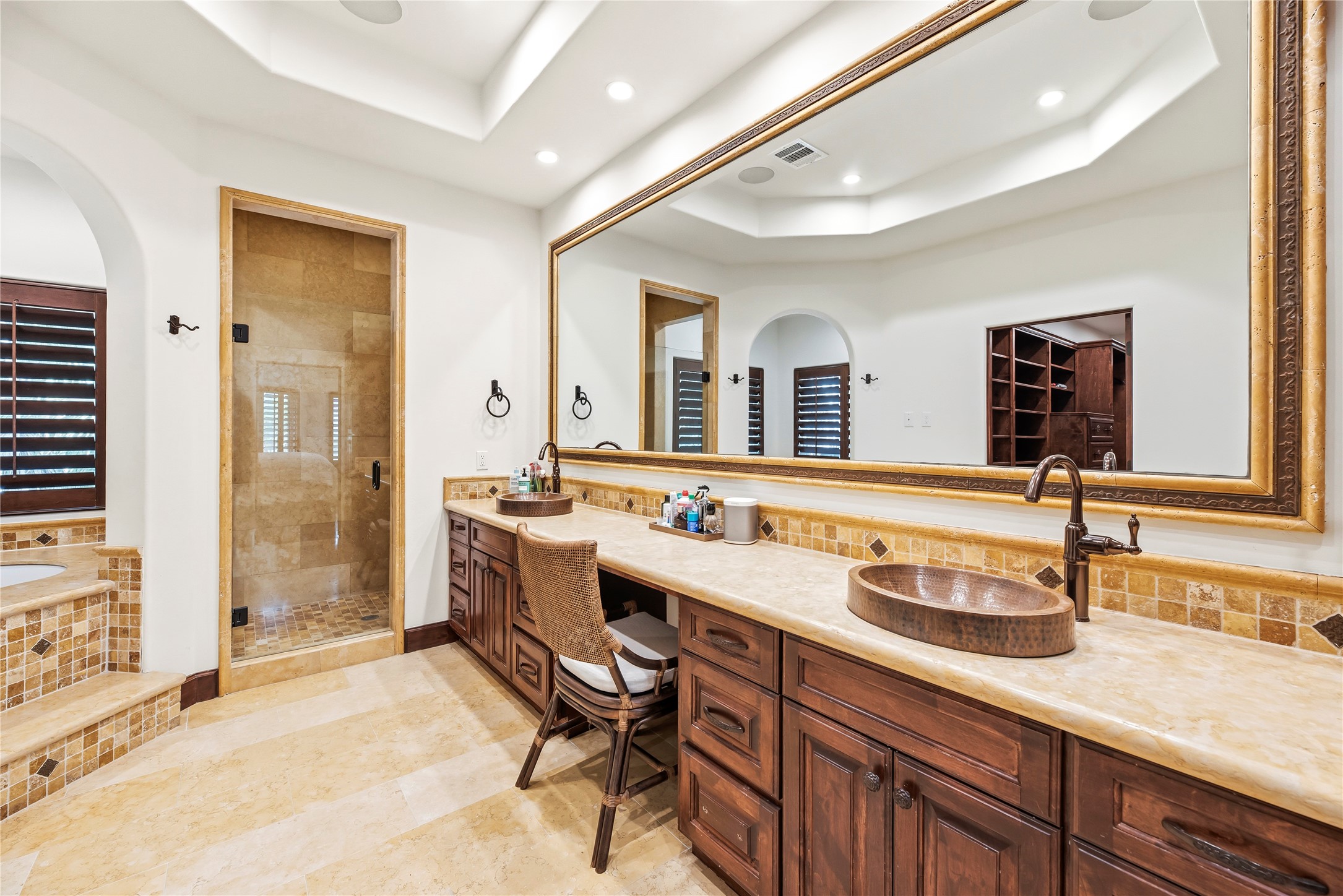 This sophisticated en-suite sanctuary features custom copper sinks set into expansive granite vanities. Every detail provides a refined atmosphere, offering a spacious and elegant environment for your morning routine.