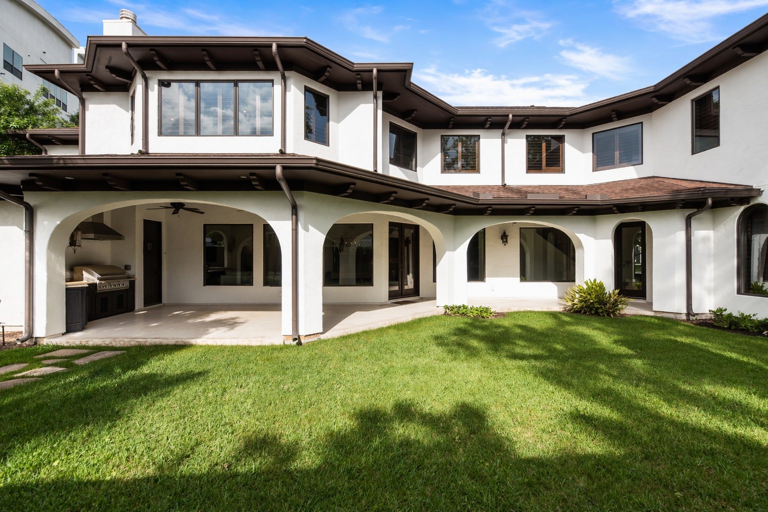 The rear exterior features a sweeping arched loggia and a built-in summer kitchen, perfectly designed for seamless indoor-outdoor living.