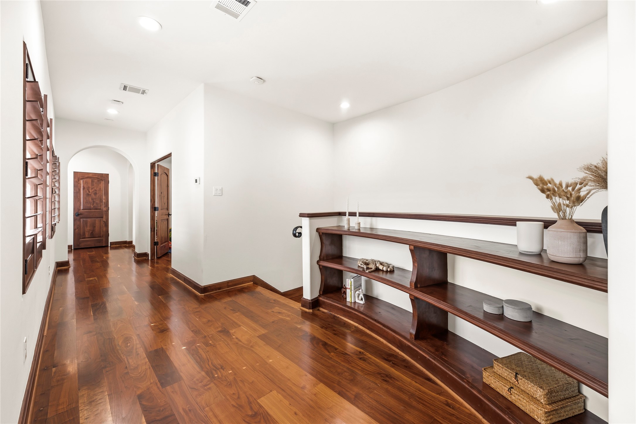 The second-floor landing continues the home's theme of quality with wood floors and built-in shelving, providing a functional transition to the sleeping quarters.