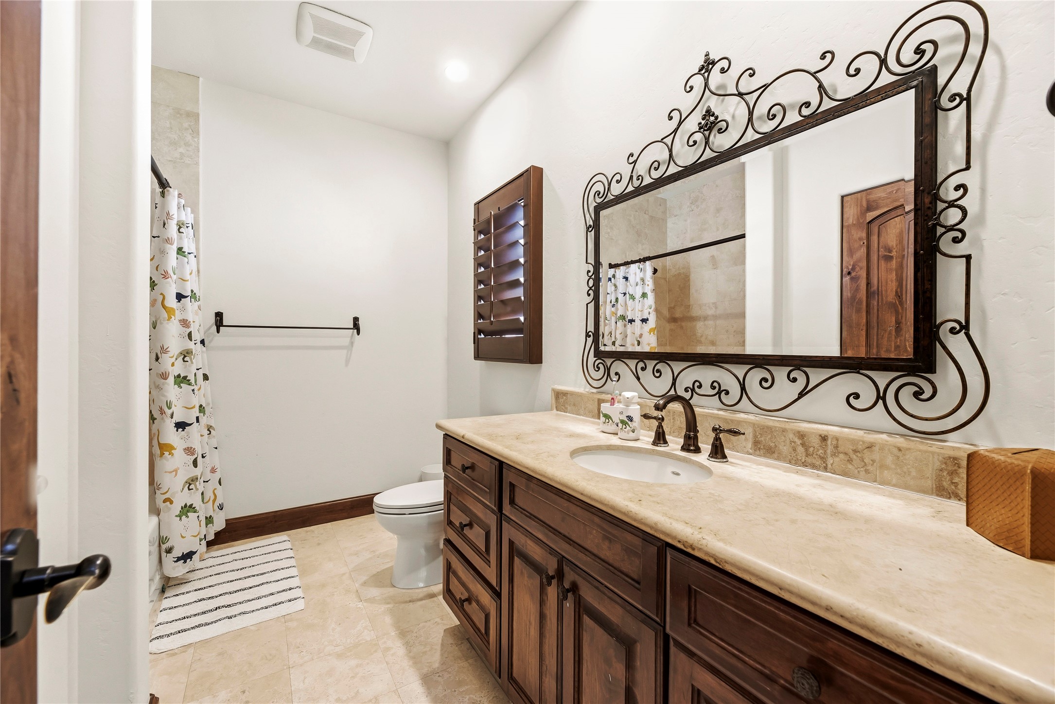 The secondary bathroom features a custom wrought-iron mirror and granite vanity, ensuring even guest spaces are treated with refined elegance.