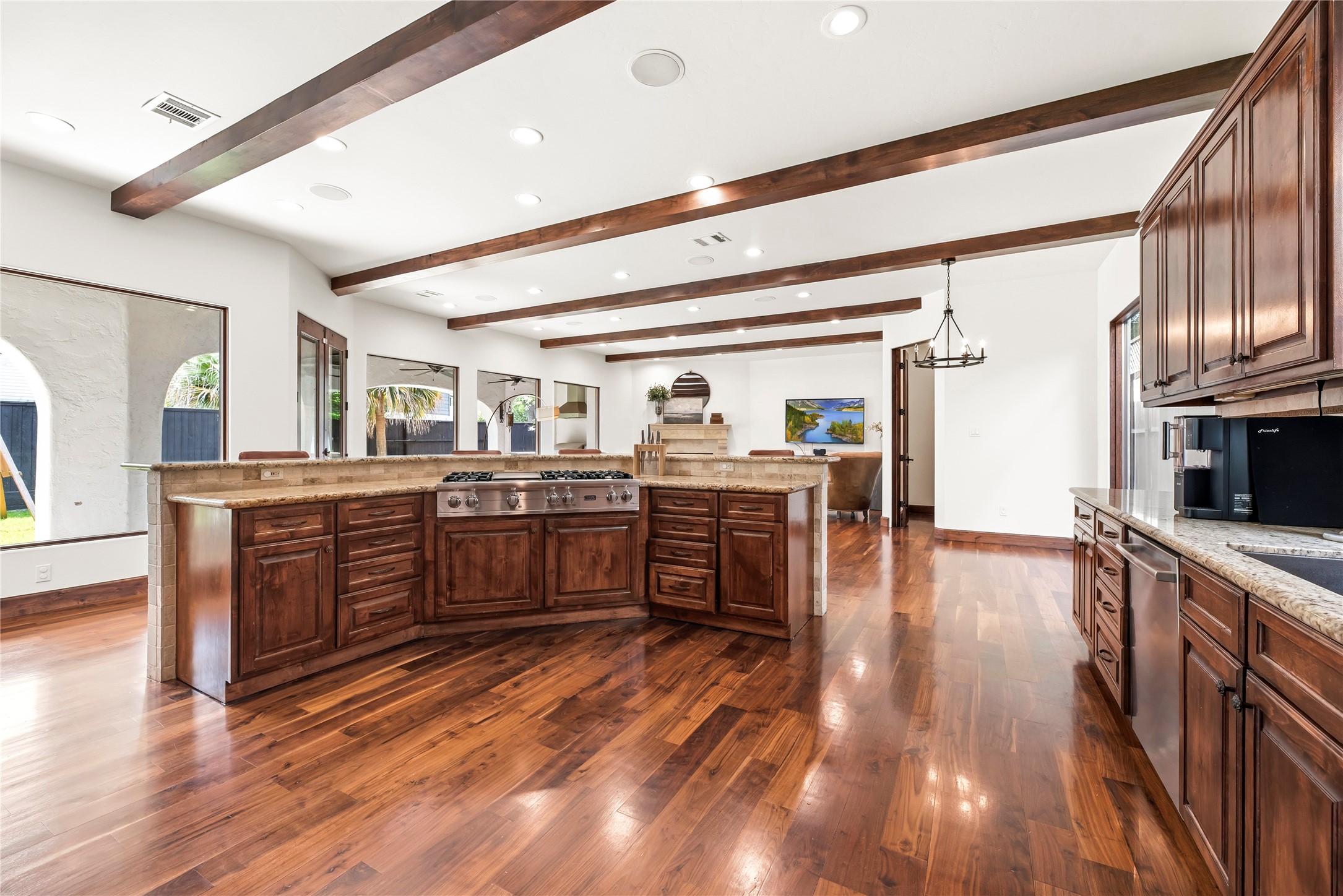The oversized island features a built-in gas cooktop and breakfast bar seating, making it the functional centerpiece of this grand culinary space.
