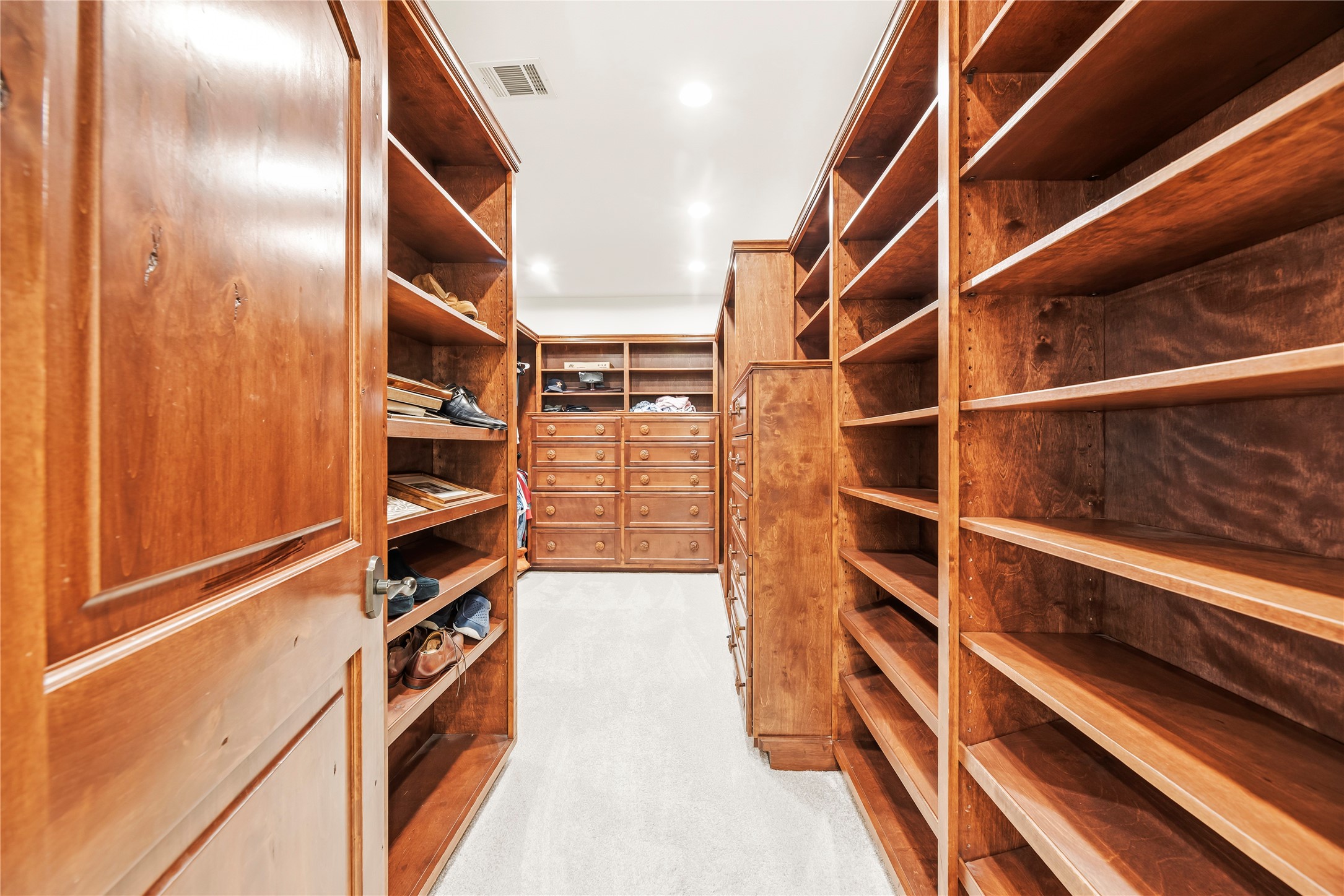 The oversized walk-in closet features floor-to-ceiling custom shelving and drawers, offering a high-end solution for a meticulously organized wardrobe.