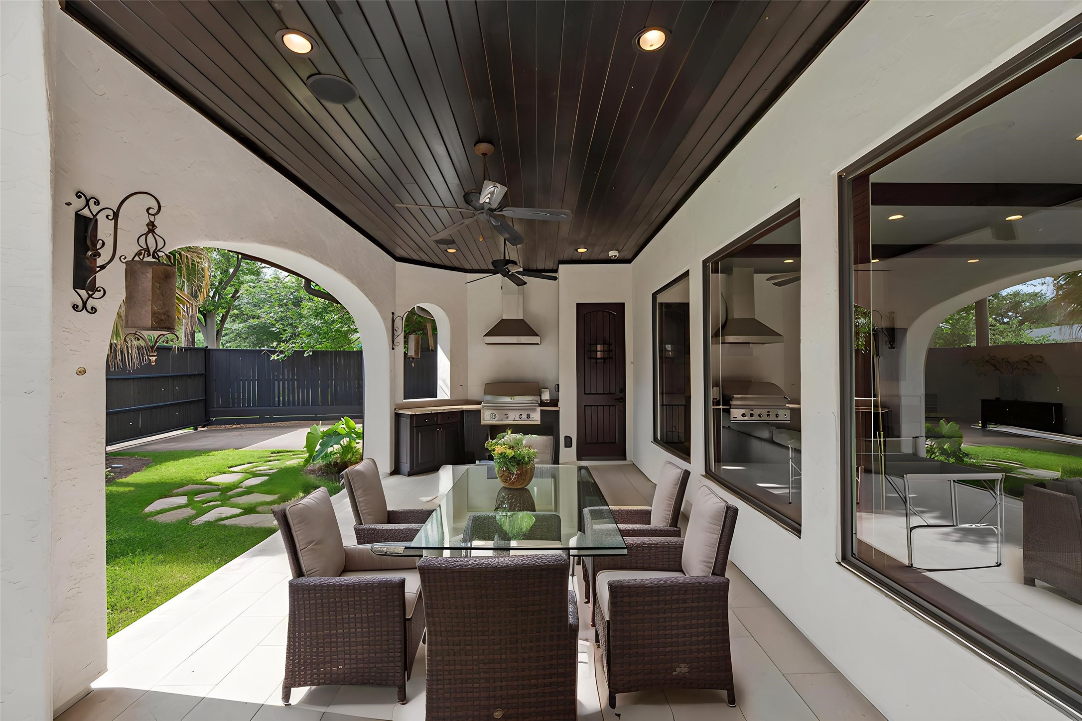 The covered patio features custom wood-plank ceilings and recessed lighting, creating a seamless transition for elegant outdoor entertaining. Virtually staged.