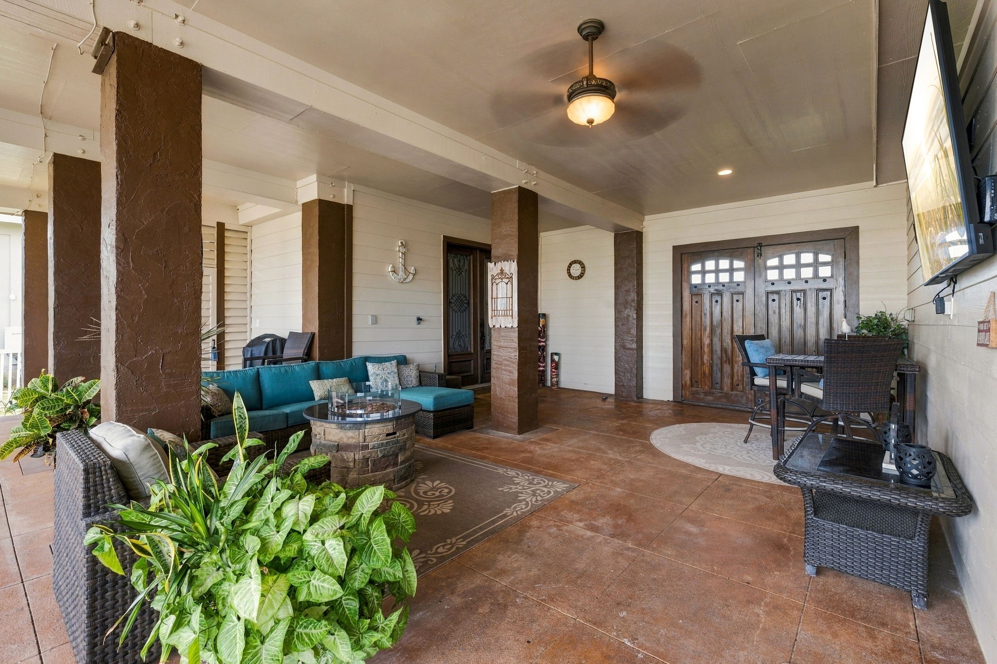 Spacious covered patio with stylish seating, ceiling fan, and rustic wooden accents, perfect for outdoor relaxation and entertaining.