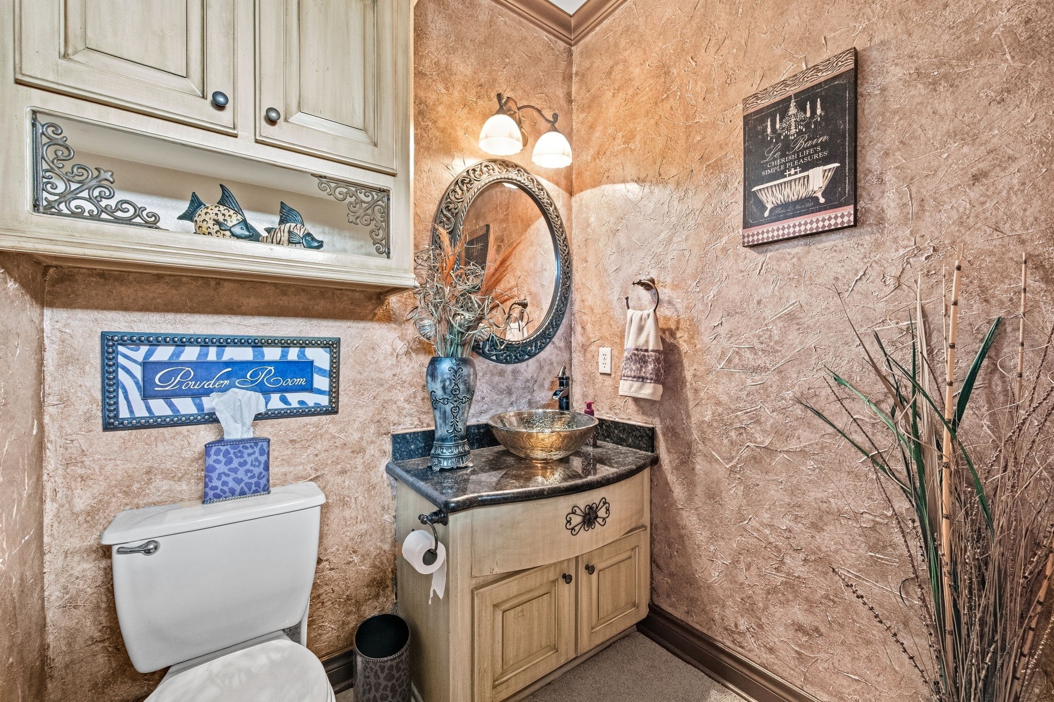 Elegant hallway powder room with textured walls, a decorative mirror, and a stylish vessel sink set on a granite countertop, complemented by charming accents and cabinetry.