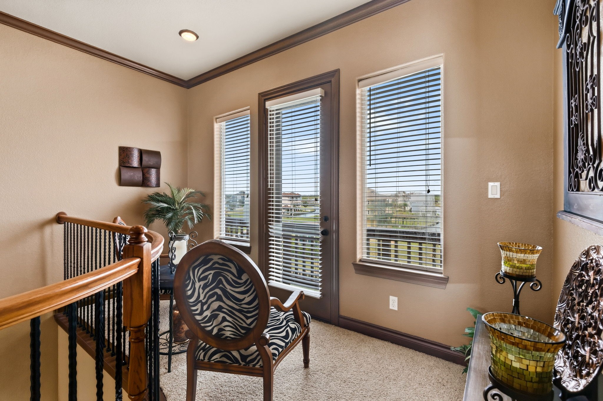 Cozy sitting area with abundant natural light, featuring elegant wood accents, a zebra-patterned chair, and access to a balcony with scenic views.