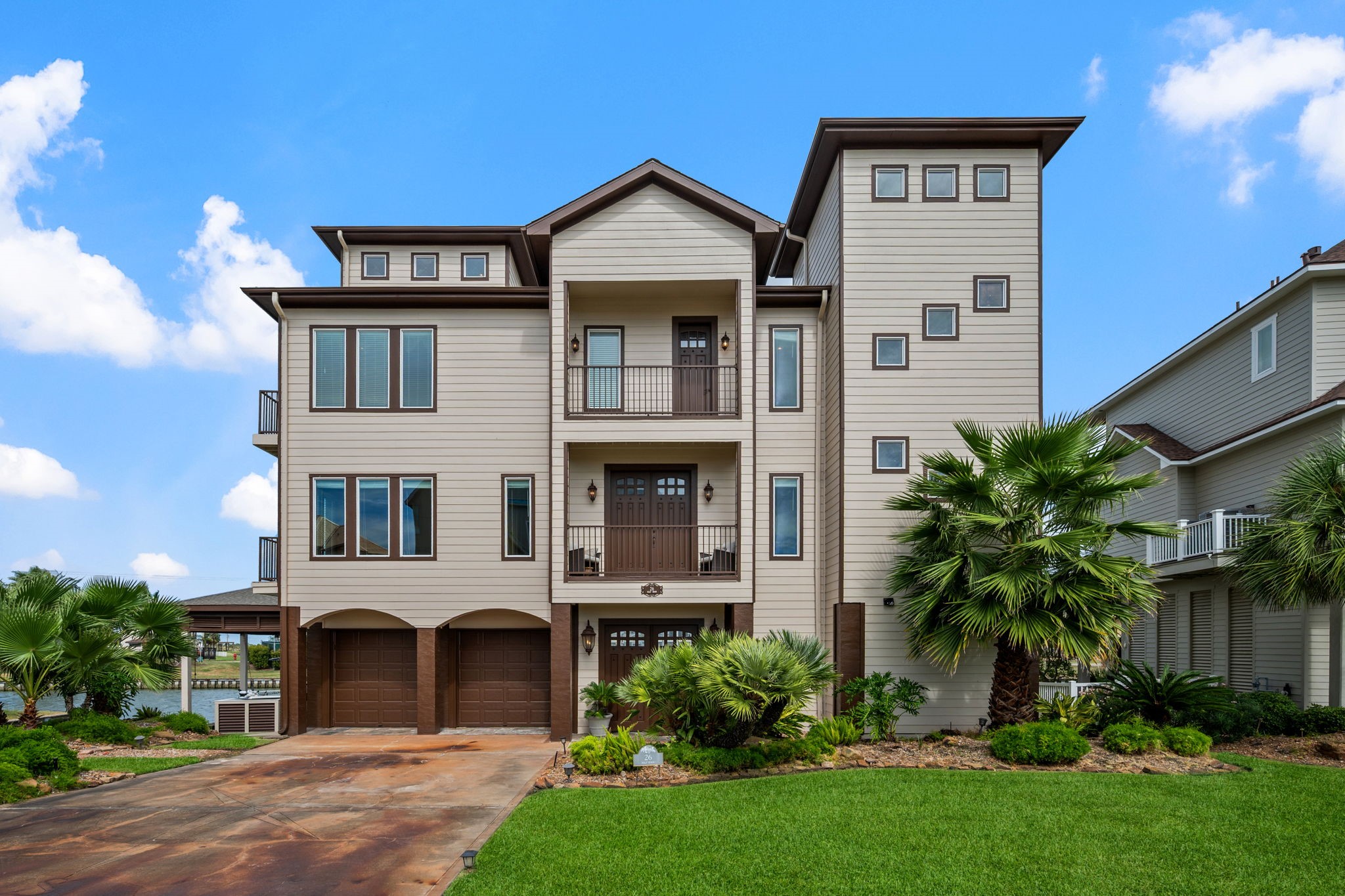 Stunning three-story coastal home with modern architecture, featuring a spacious driveway, lush landscaping, and elegant balconies perfect for enjoying serene views. Stunning three-story coastal home with modern architecture, featuring a spacious driveway, lush landscaping, and elegant balconies perfect for enjoying serene views.