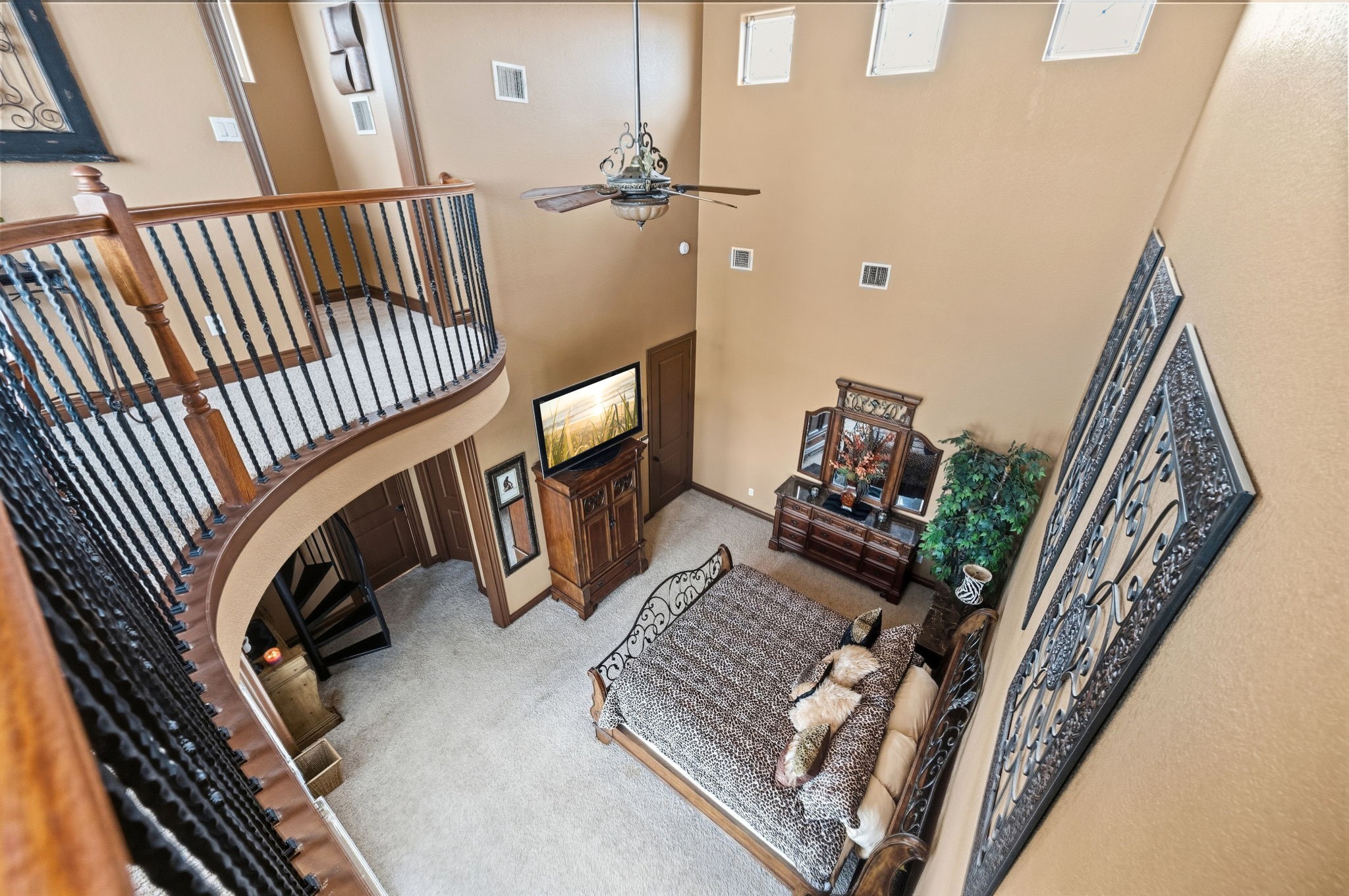 Grand two-story bedroom with elegant wrought iron balcony, high ceilings, and abundant natural light.