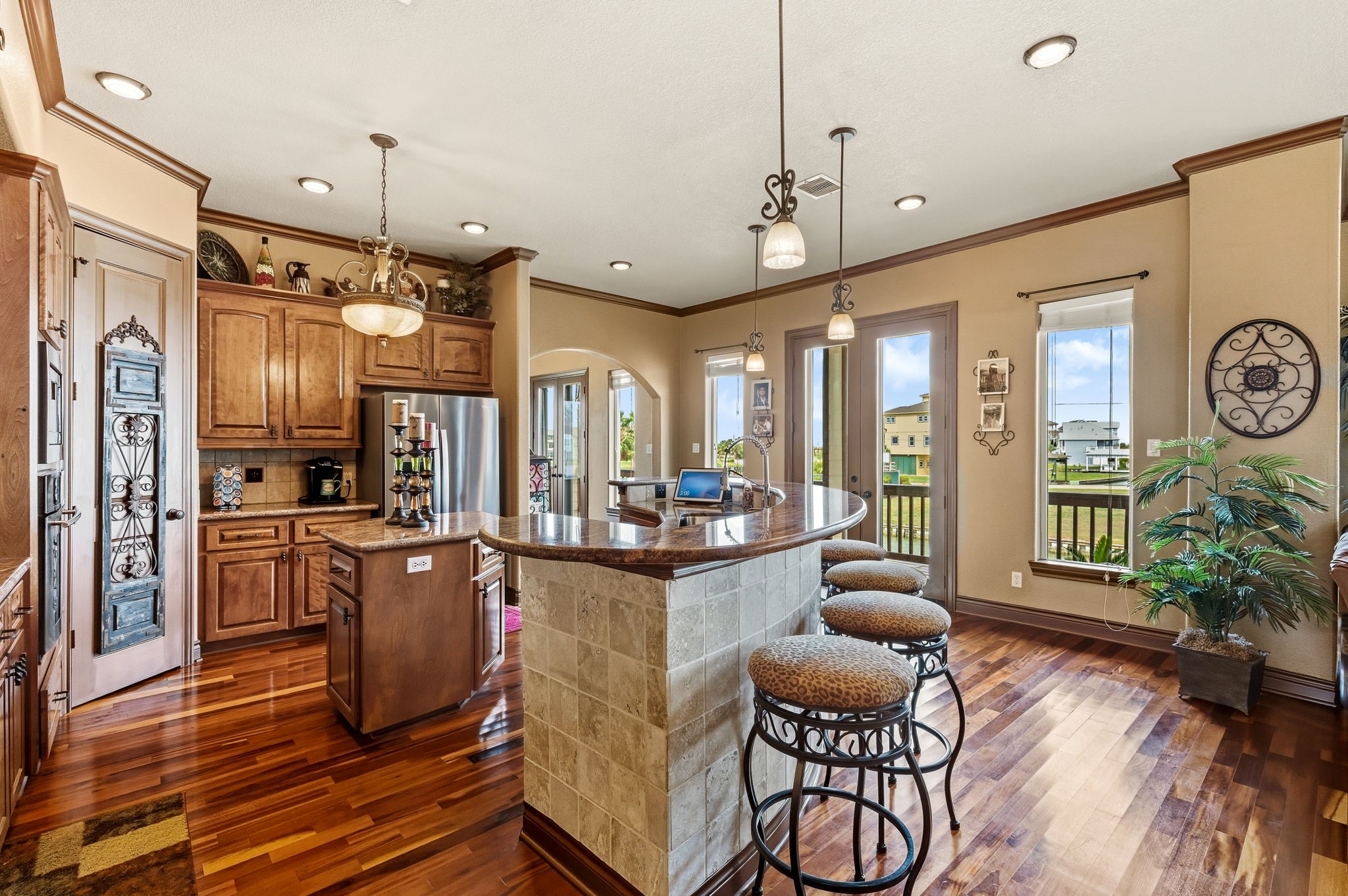 Elegant kitchen with rich wood cabinetry, stainless steel appliances, and a stylish breakfast bar. The open layout and ample natural light create a warm and inviting atmosphere, perfect for entertaining.