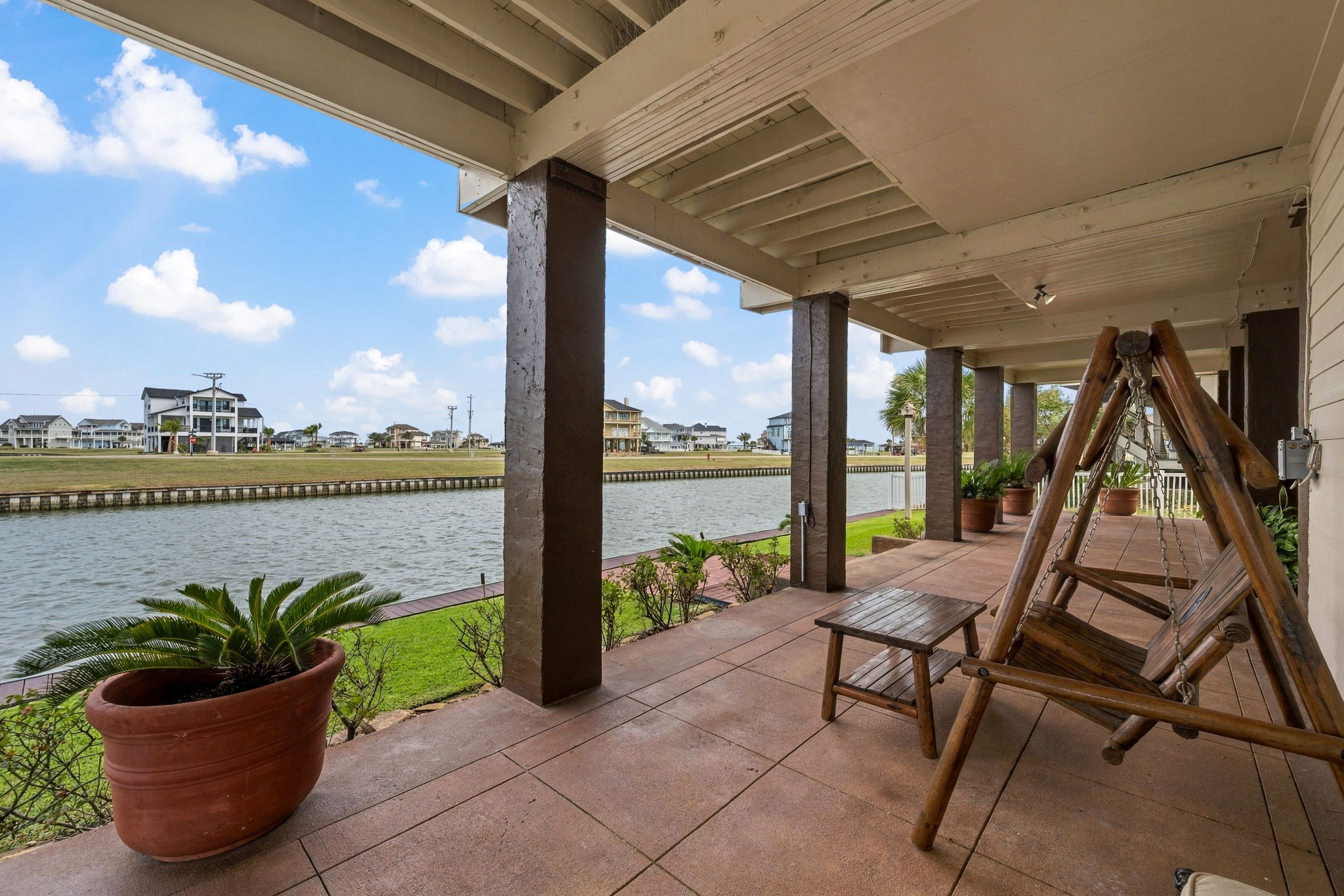 Charming waterfront patio with a cozy wooden swing and serene canal views, perfect for relaxing and enjoying the outdoors.