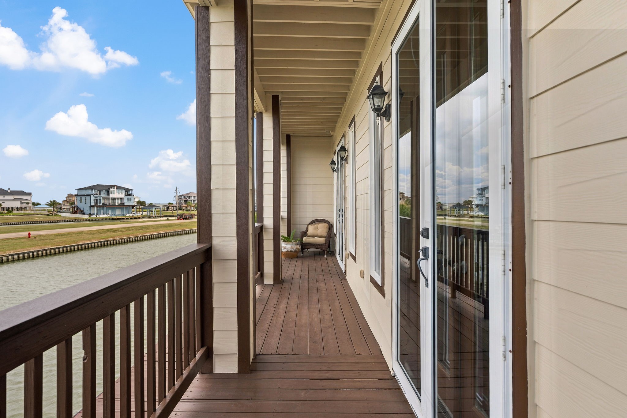 Charming waterfront balcony with elegant wood flooring and glass doors, offering serene canal views and a peaceful retreat.