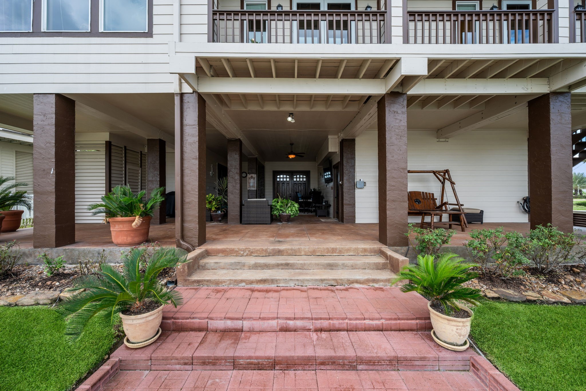 Charming covered patio featuring elegant columns, cozy seating area, and lush potted greenery, perfect for relaxation and entertaining. Charming covered patio featuring elegant columns, cozy seating area, and lush potted greenery, perfect for relaxation and entertaining.