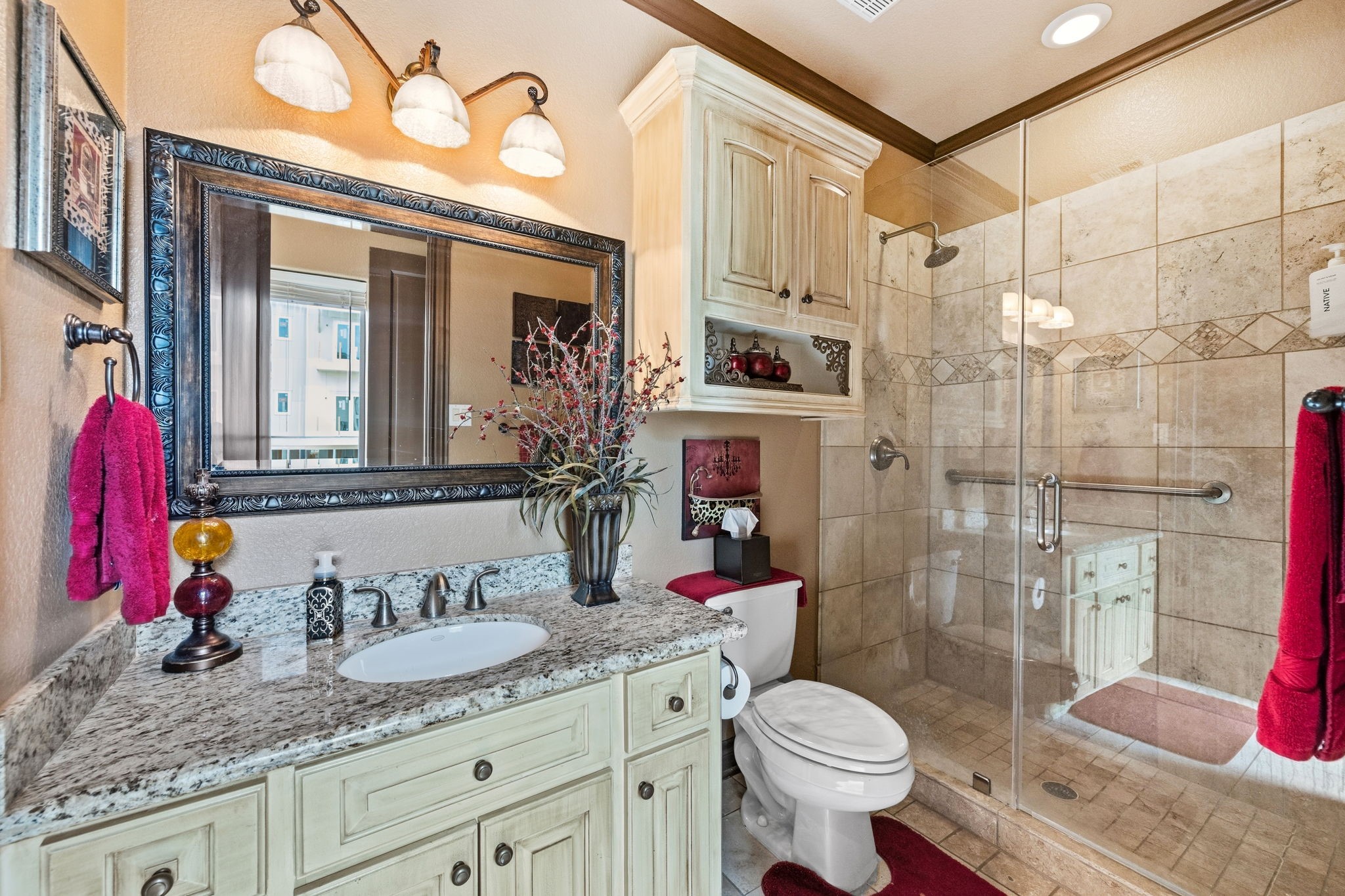 Elegant ensuite bathroom featuring a granite countertop, large framed mirror, and a spacious glass-enclosed shower with stylish tilework.