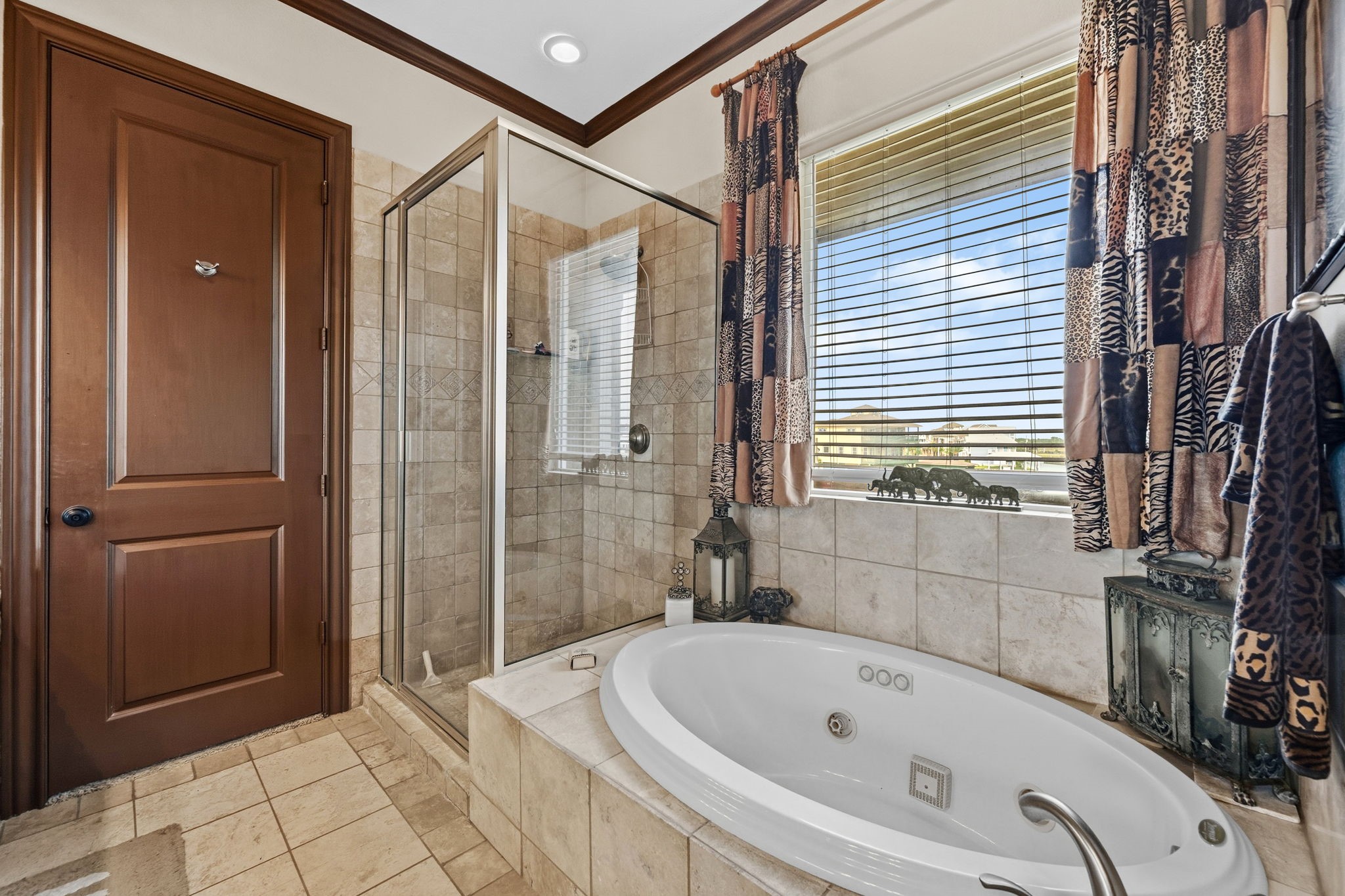 Luxurious bathroom featuring a spacious tiled shower and a relaxing jacuzzi tub, accented by elegant curtains and warm wood finishes.