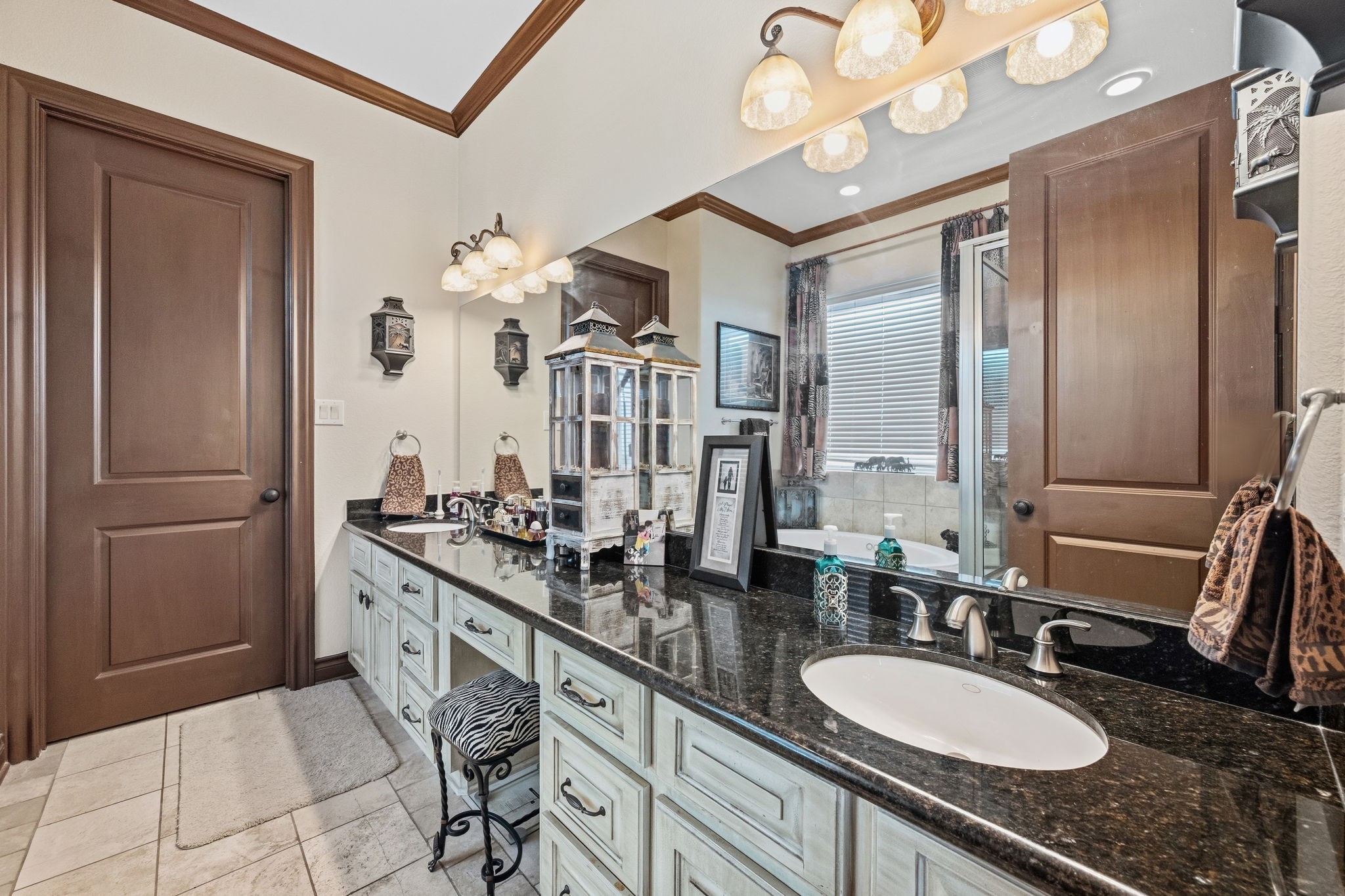 Elegant bathroom featuring a double sink vanity with sleek granite countertops, stylish lighting, and ample storage, complemented by a cozy bathtub for relaxation.