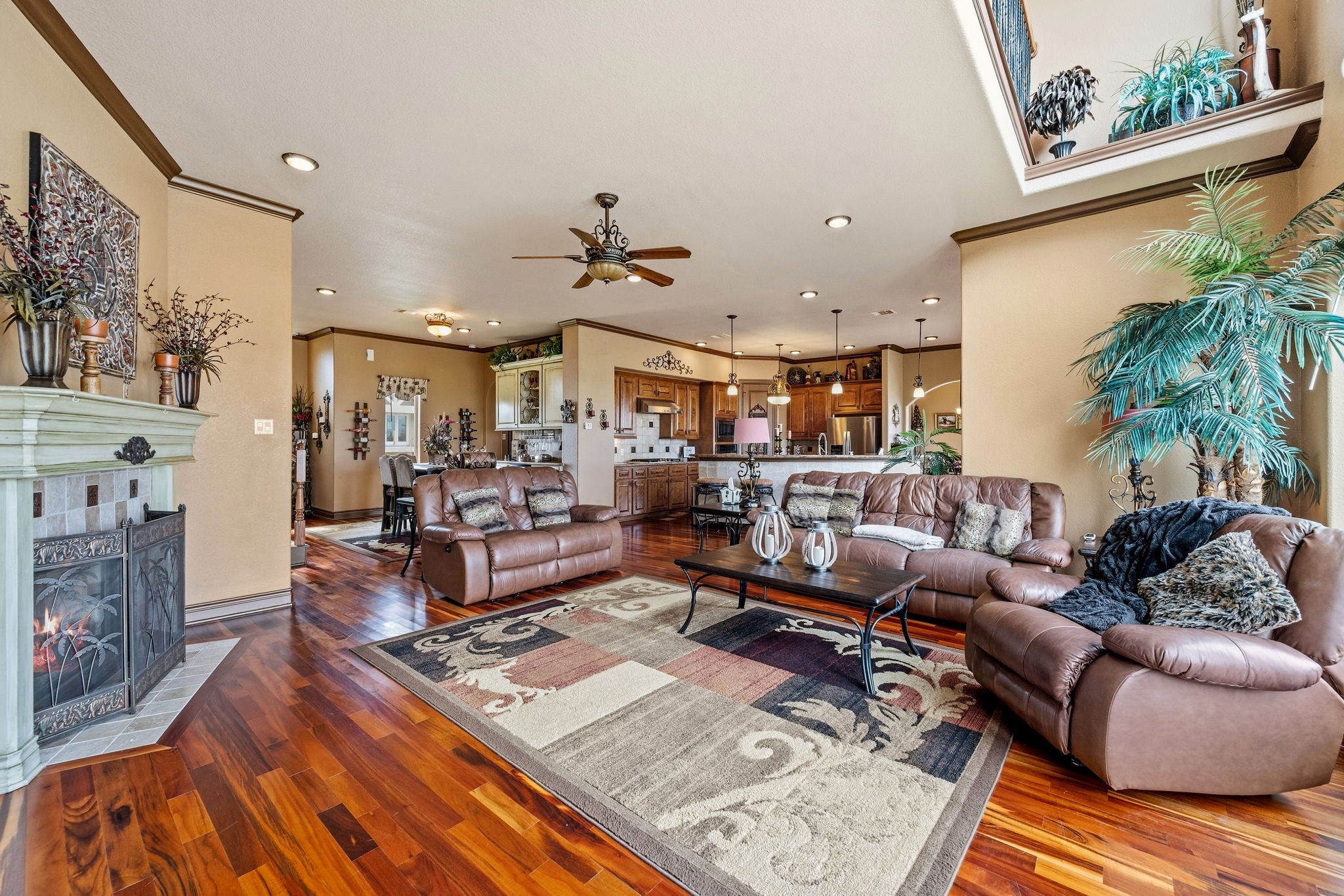Spacious living area with rich wood flooring, cozy fireplace, and ample natural light, seamlessly connecting to a modern kitchen and dining space.