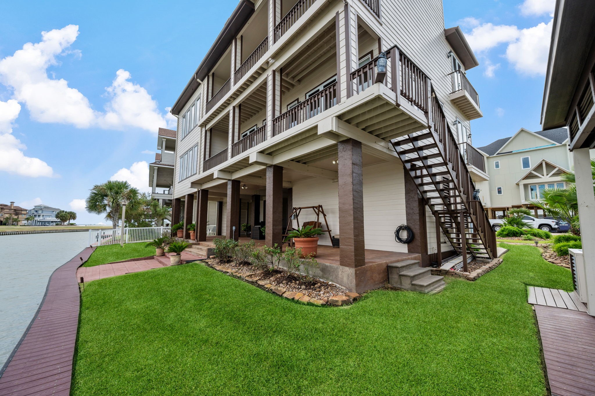 Stunning waterfront home with multi-level balconies, lush landscaping, and direct access to a serene canal, perfect for outdoor living and relaxation.