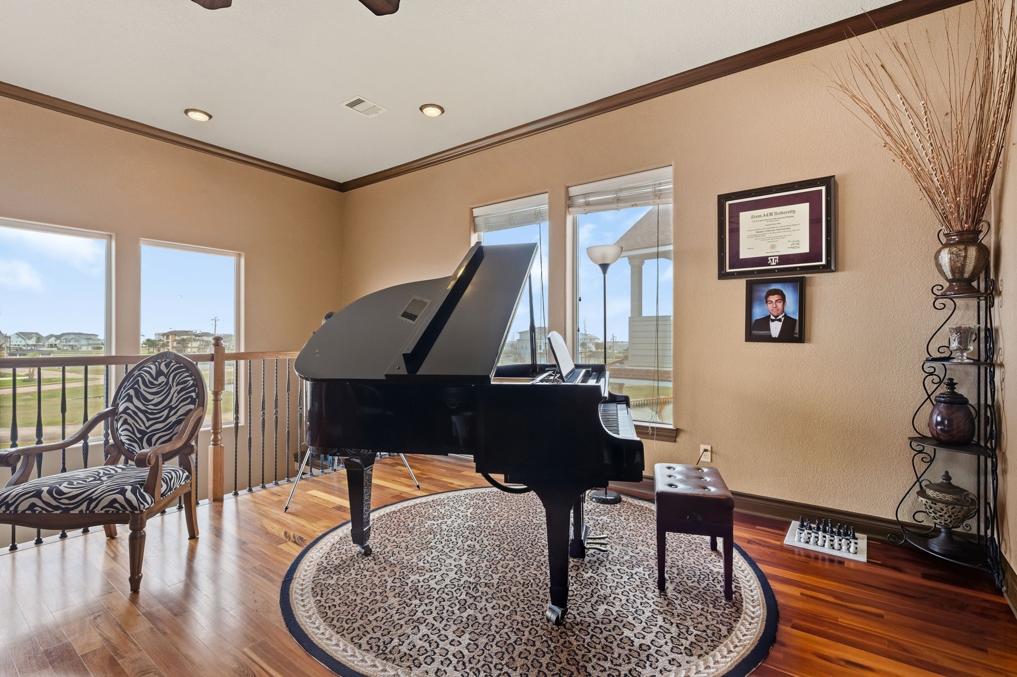 Elegant music room featuring a grand piano, rich wood flooring, and ample natural light from large windows, creating a perfect ambiance for relaxation and creativity.