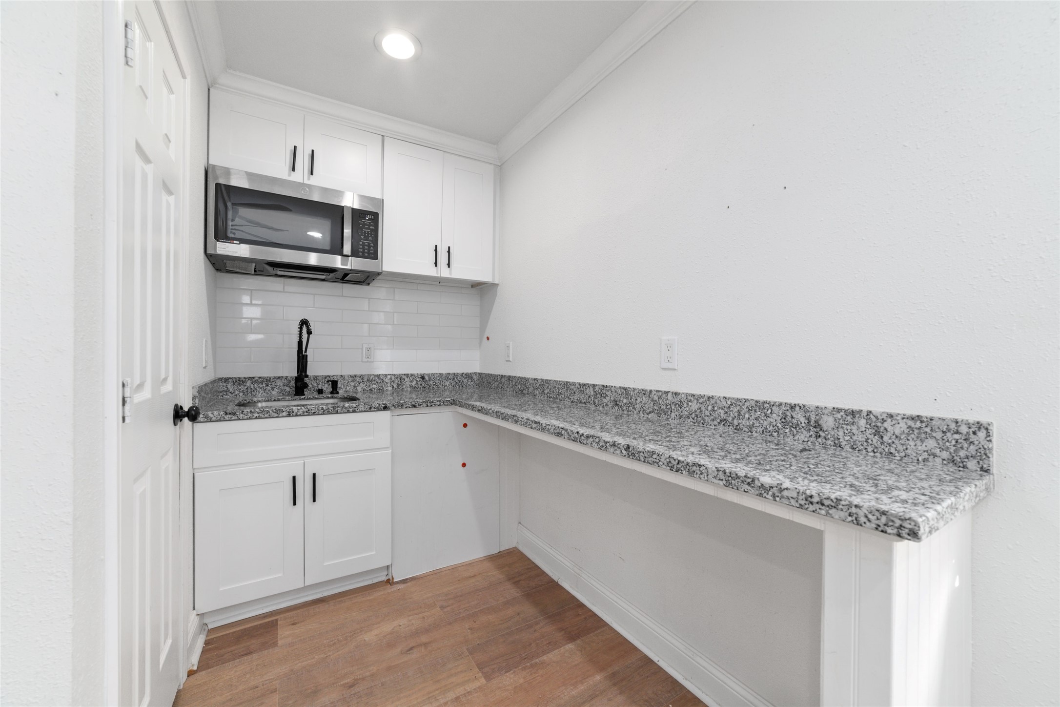 Mini kitchen space with a microwave and a sink.