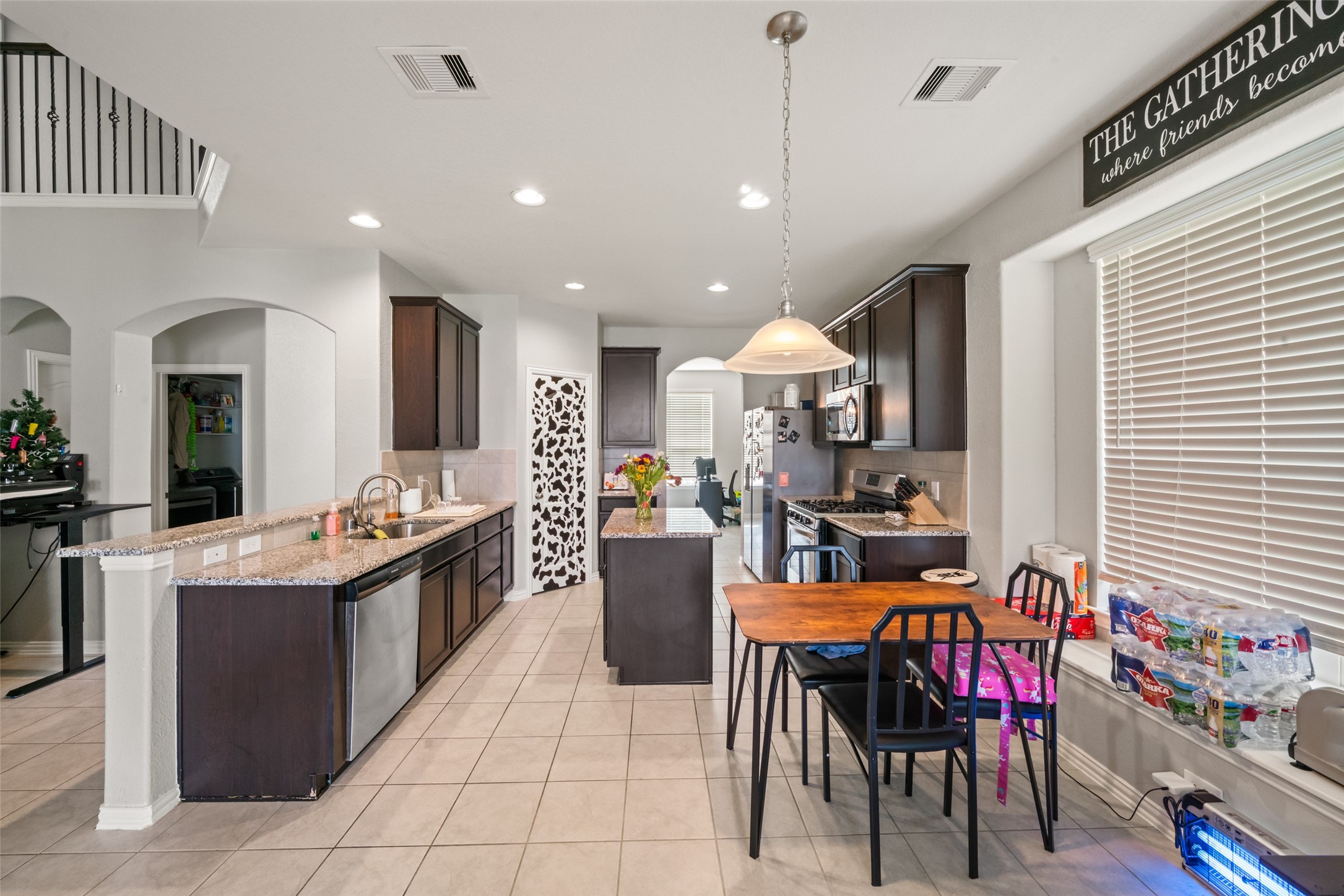Spacious kitchen with sleek dark cabinetry, stainless steel appliances, and a cozy breakfast nook, all under soft, natural lighting.