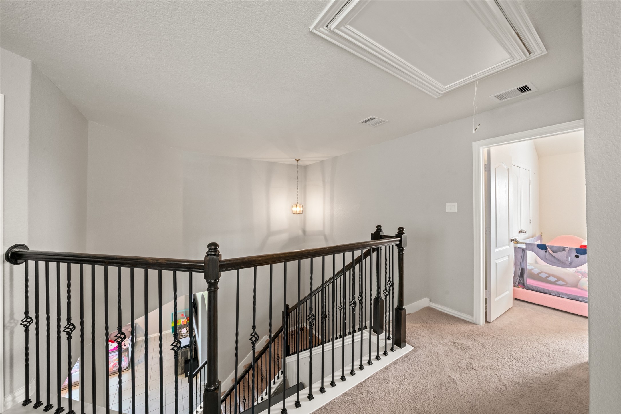 Elegant upper landing with a stylish wrought iron railing, plush carpeting, and a cozy adjacent bedroom.