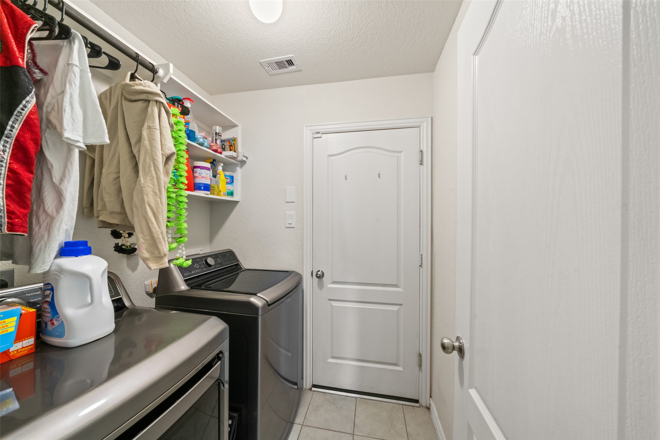 Efficient laundry room with modern appliances, ample shelving for organization, and hanging space for clothes.