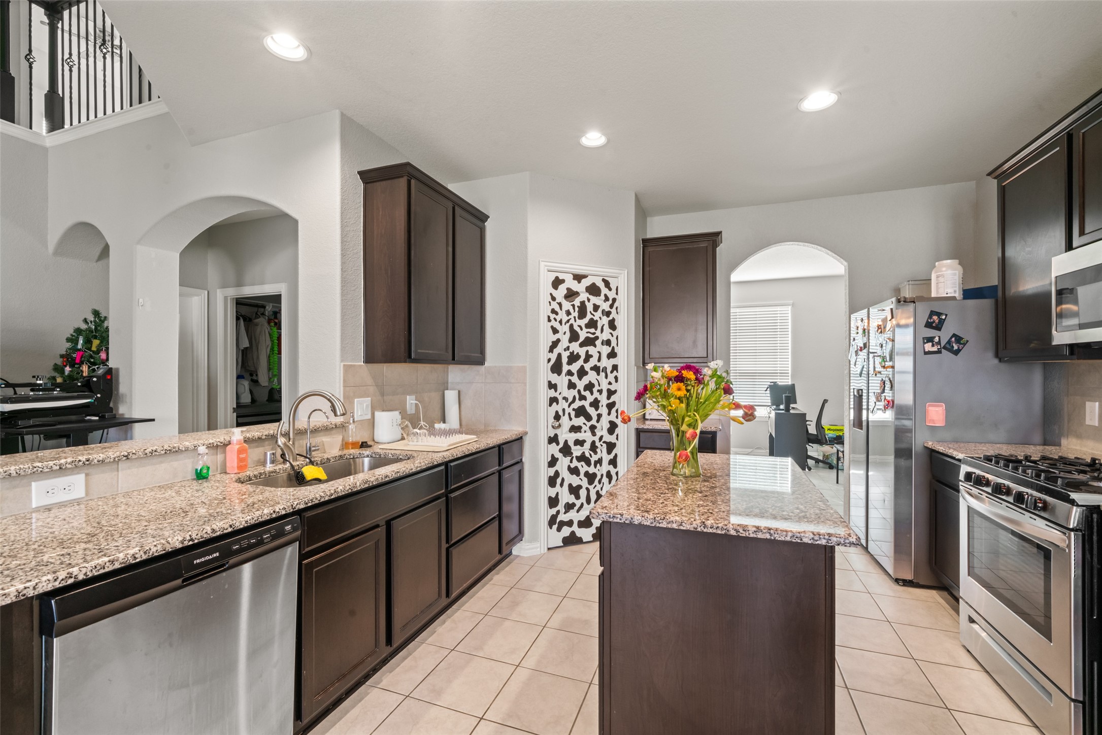 Modern kitchen with granite countertops, stainless steel appliances, and dark wood cabinetry. An island with a floral centerpiece adds charm, while arched doorways provide an elegant touch. Modern kitchen with granite countertops, stainless steel appliances, and dark wood cabinetry. An island with a floral centerpiece adds charm, while arched doorways provide an elegant touch.