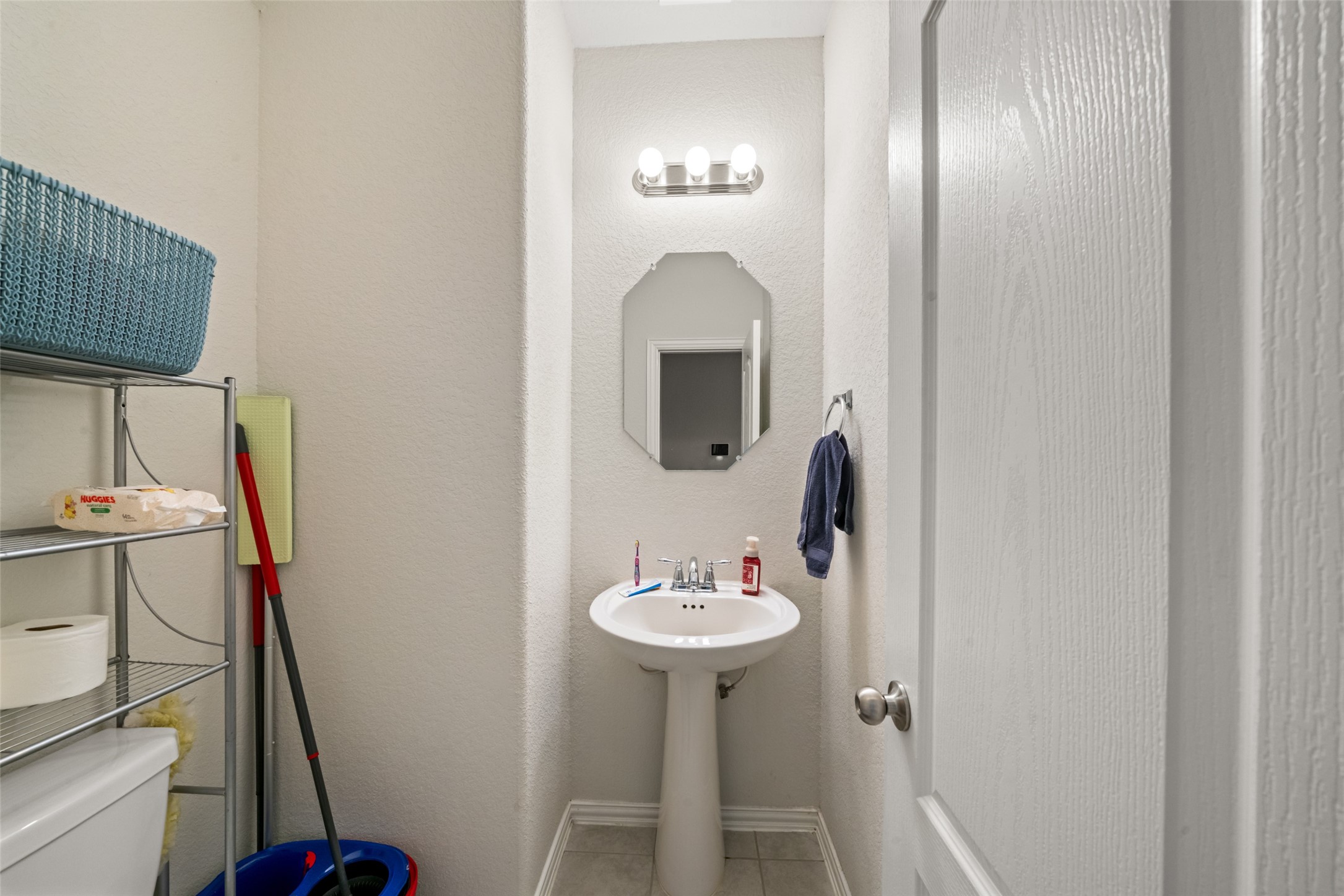 Compact powder room with a pedestal sink, mirror, and enough room to add shelving of your desire.