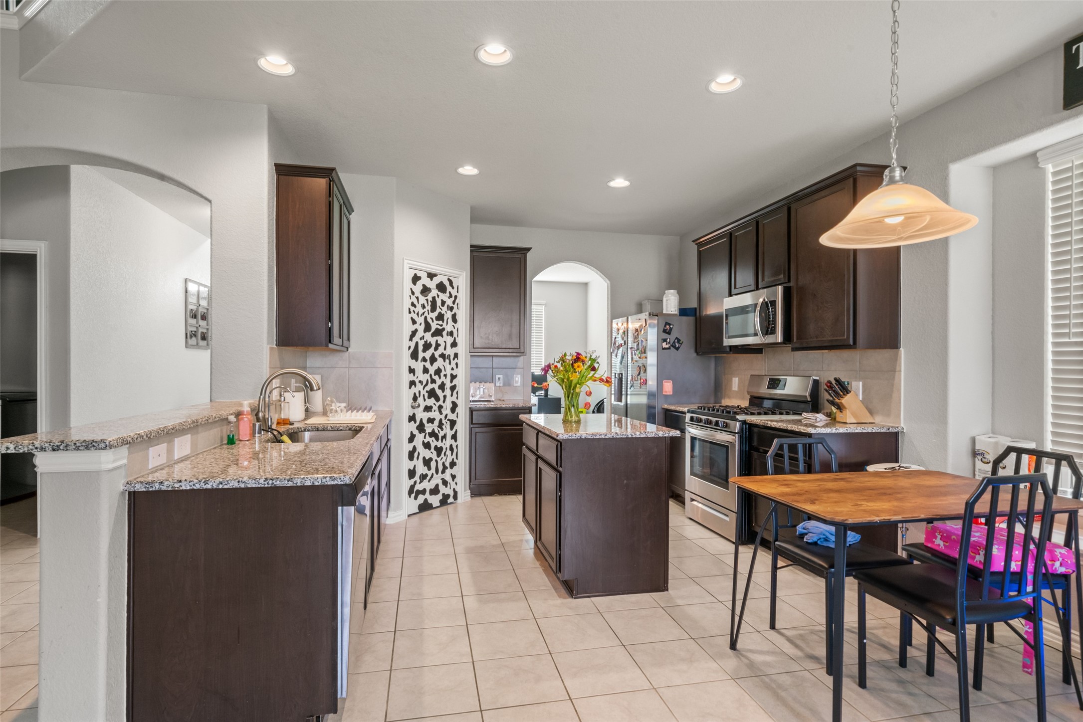 Bright and modern kitchen with dark wood cabinetry, granite countertops, and stainless steel appliances. Features a central island, cozy dining area, and ample lighting. Bright and modern kitchen with dark wood cabinetry, granite countertops, and stainless steel appliances. Features a central island, cozy dining area, and ample lighting.