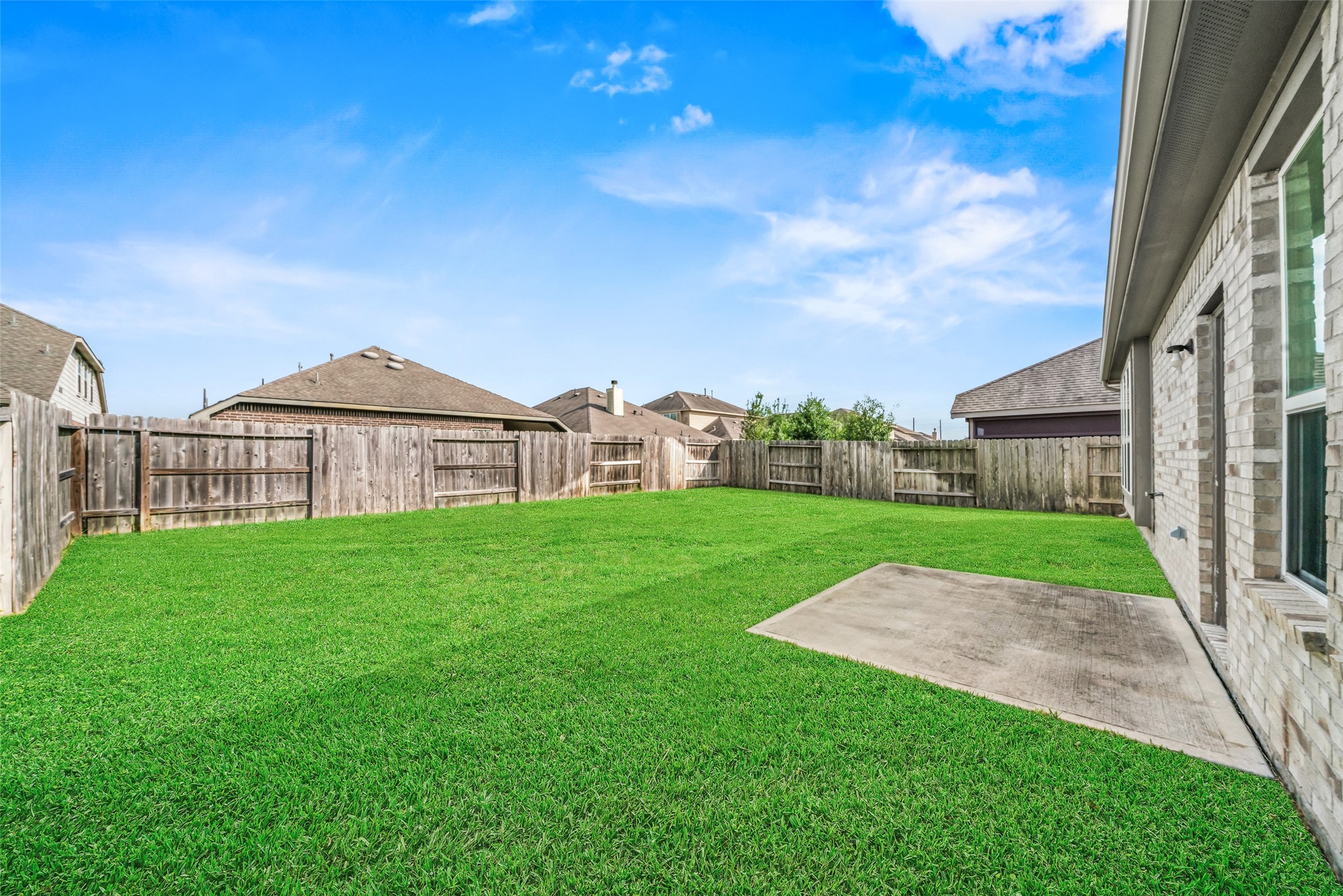 Spacious backyard with lush green lawn, bordered by a wooden fence, perfect for outdoor activities and relaxation. Spacious backyard with lush green lawn, bordered by a wooden fence, perfect for outdoor activities and relaxation.