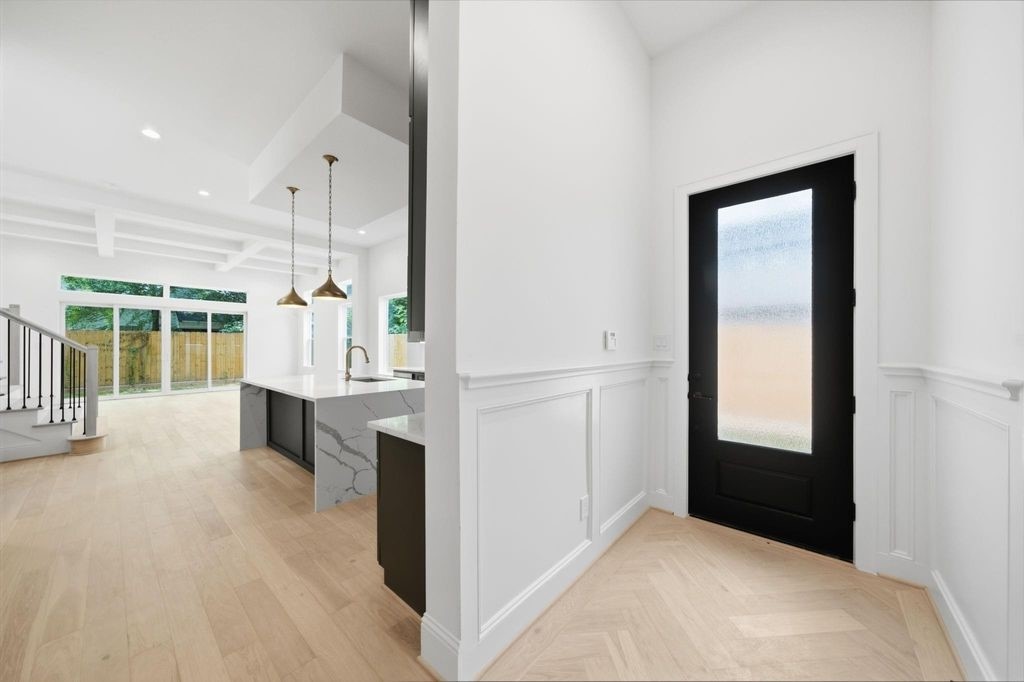 Welcoming front door entry with custom wall paneling and herringbone oak floors.