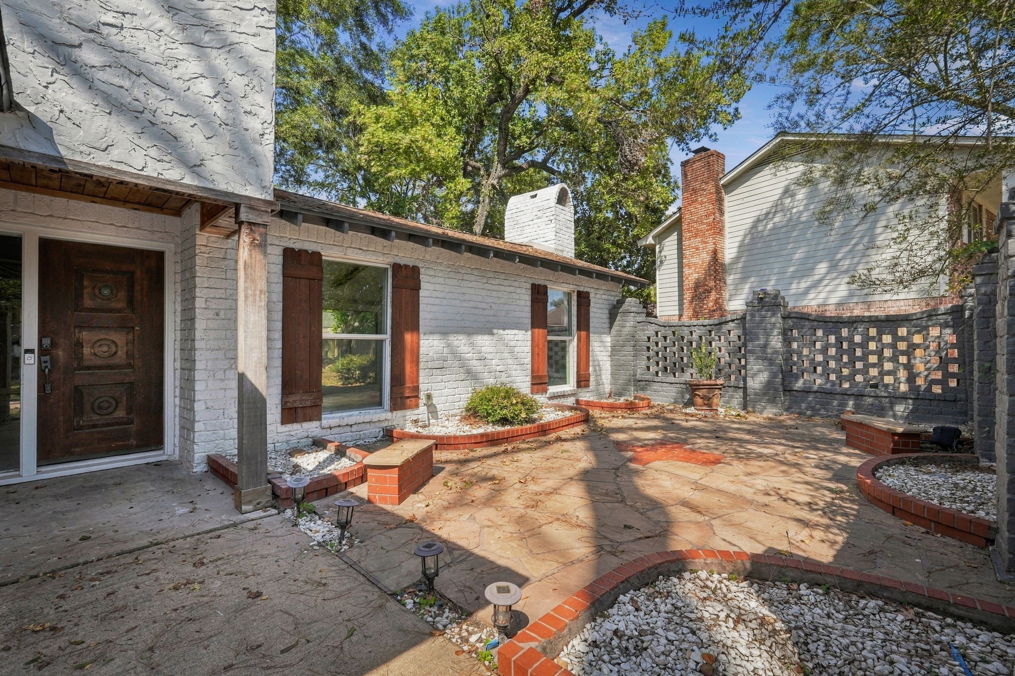 This courtyard entry with brick fencing creates a welcoming and serene outdoor space.