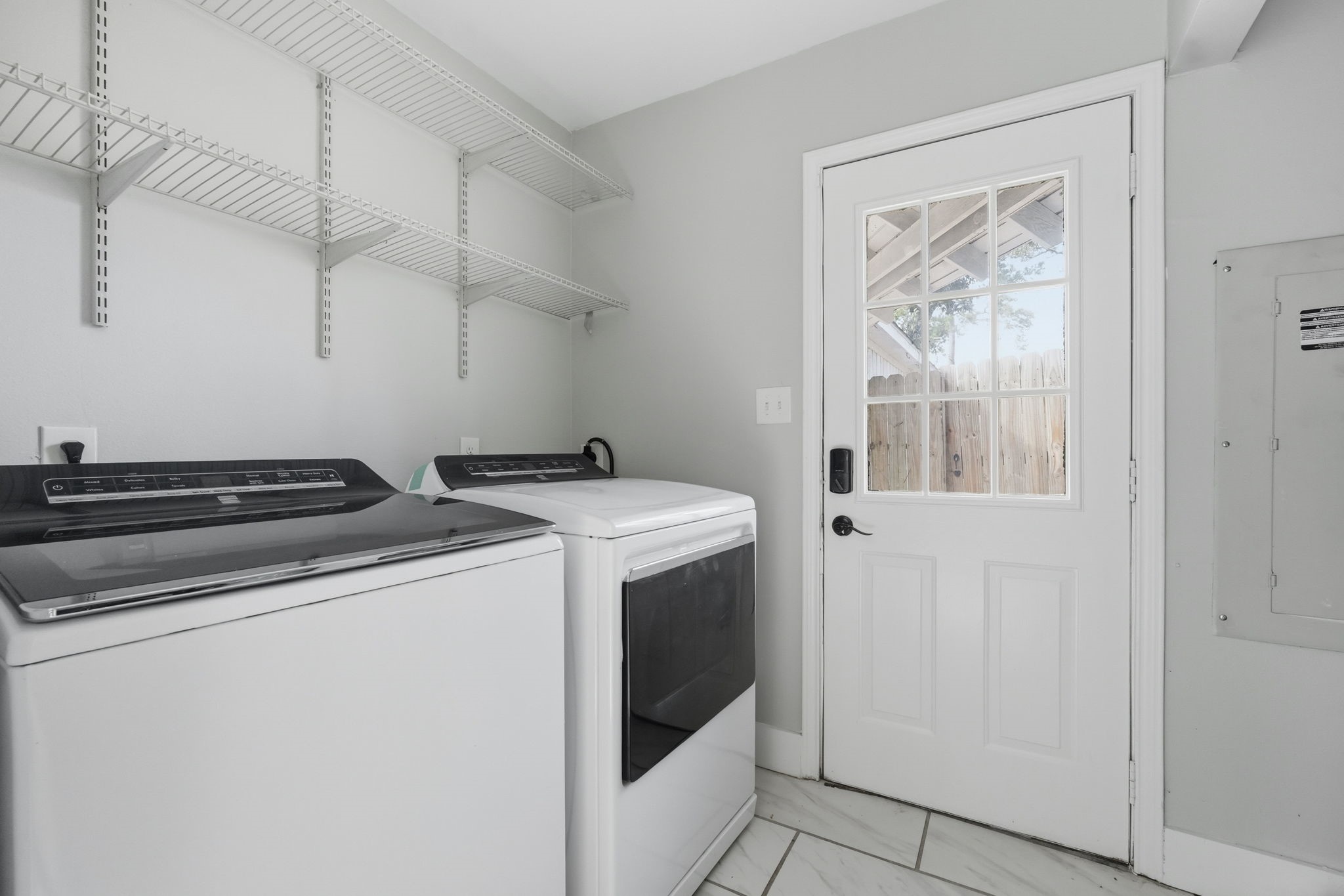 This functional laundry room features modern appliances, shelving, and convenient outdoor access.