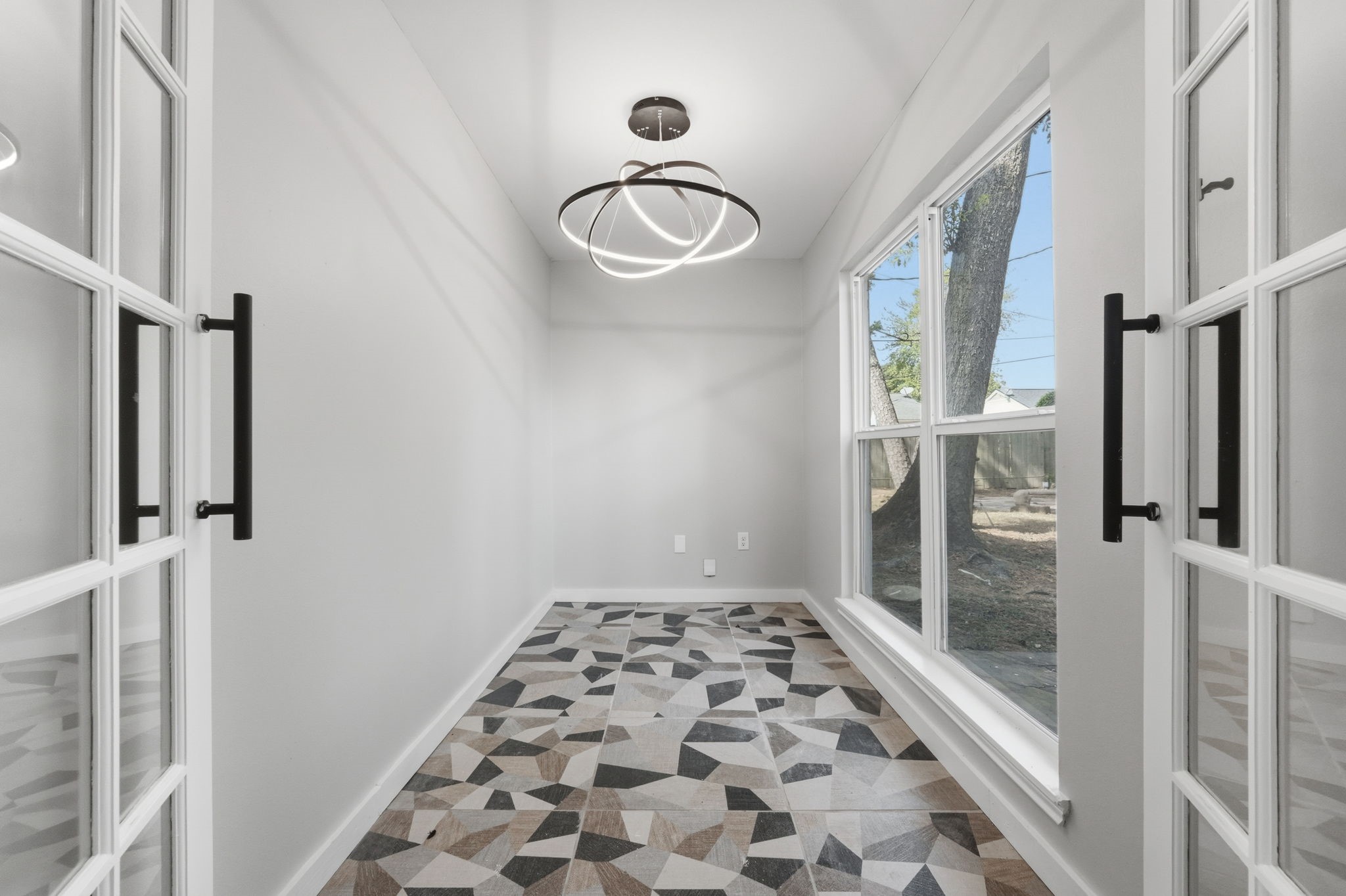 This quaint study features large windows and french doors with modern geometric flooring.