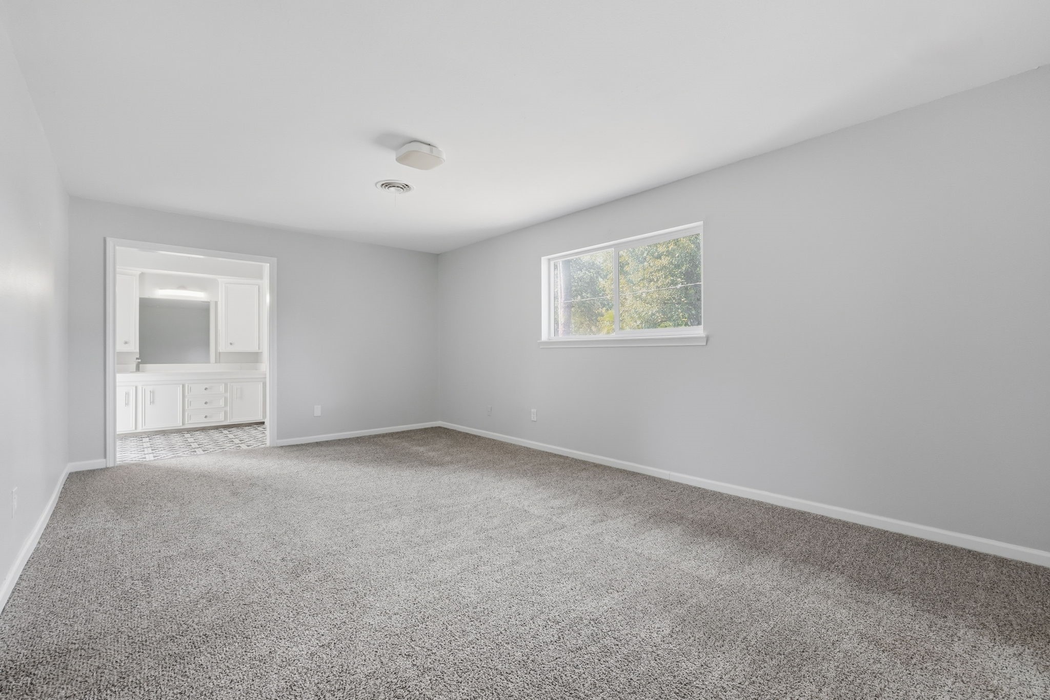 This bedroom has a large window for natural light, and an ensuite bathroom for convenience.