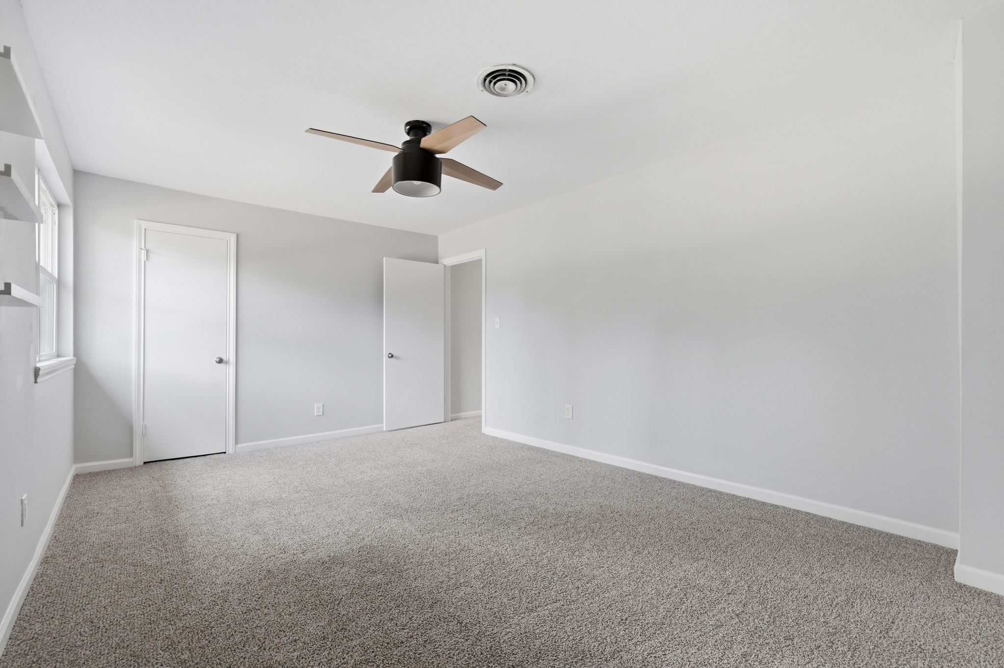 This large bedroom features a modern ceiling fan and bright natural light.