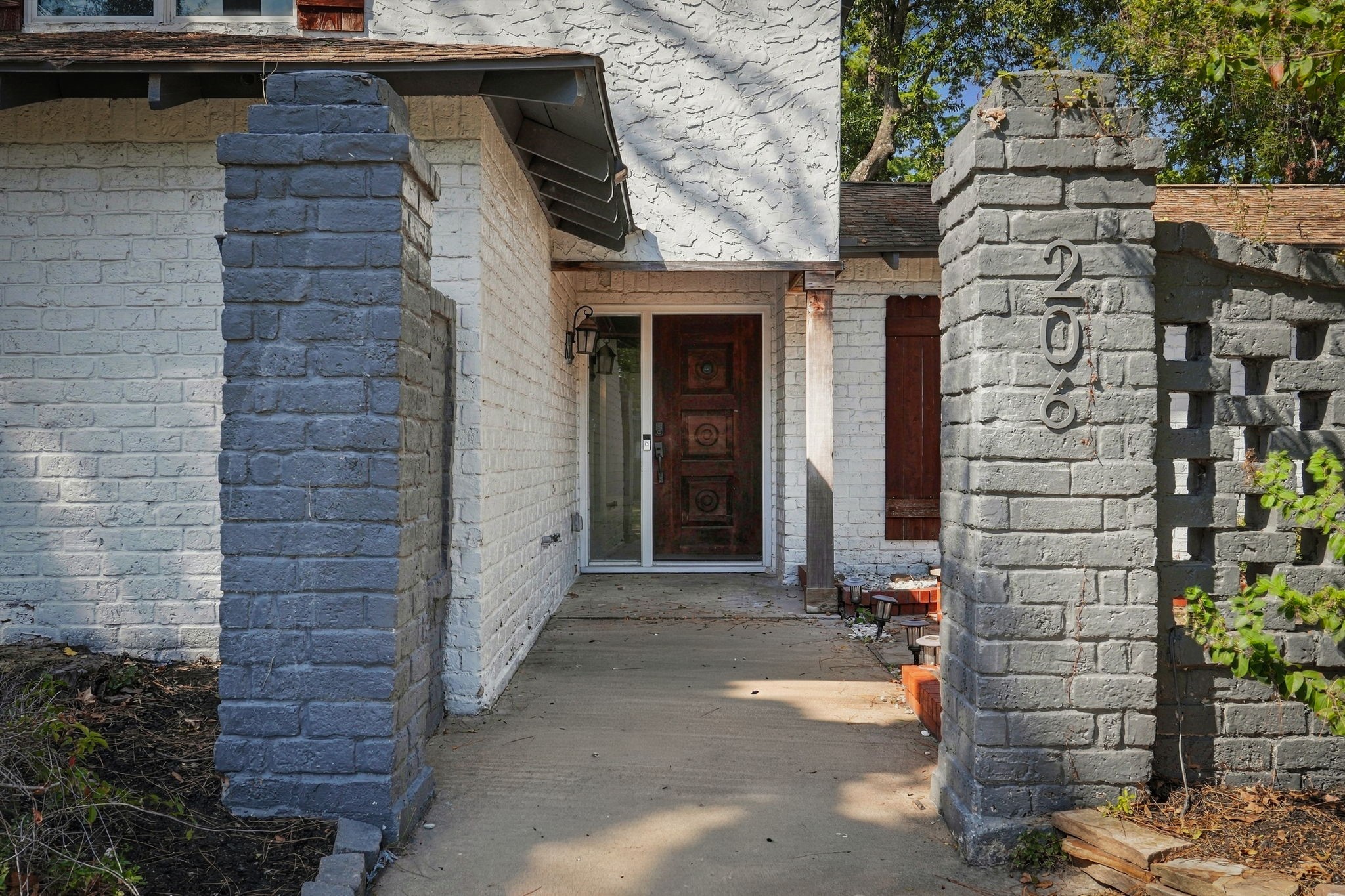 The brick pillars and rustic wooden door offer a warm welcome to this cozy home.